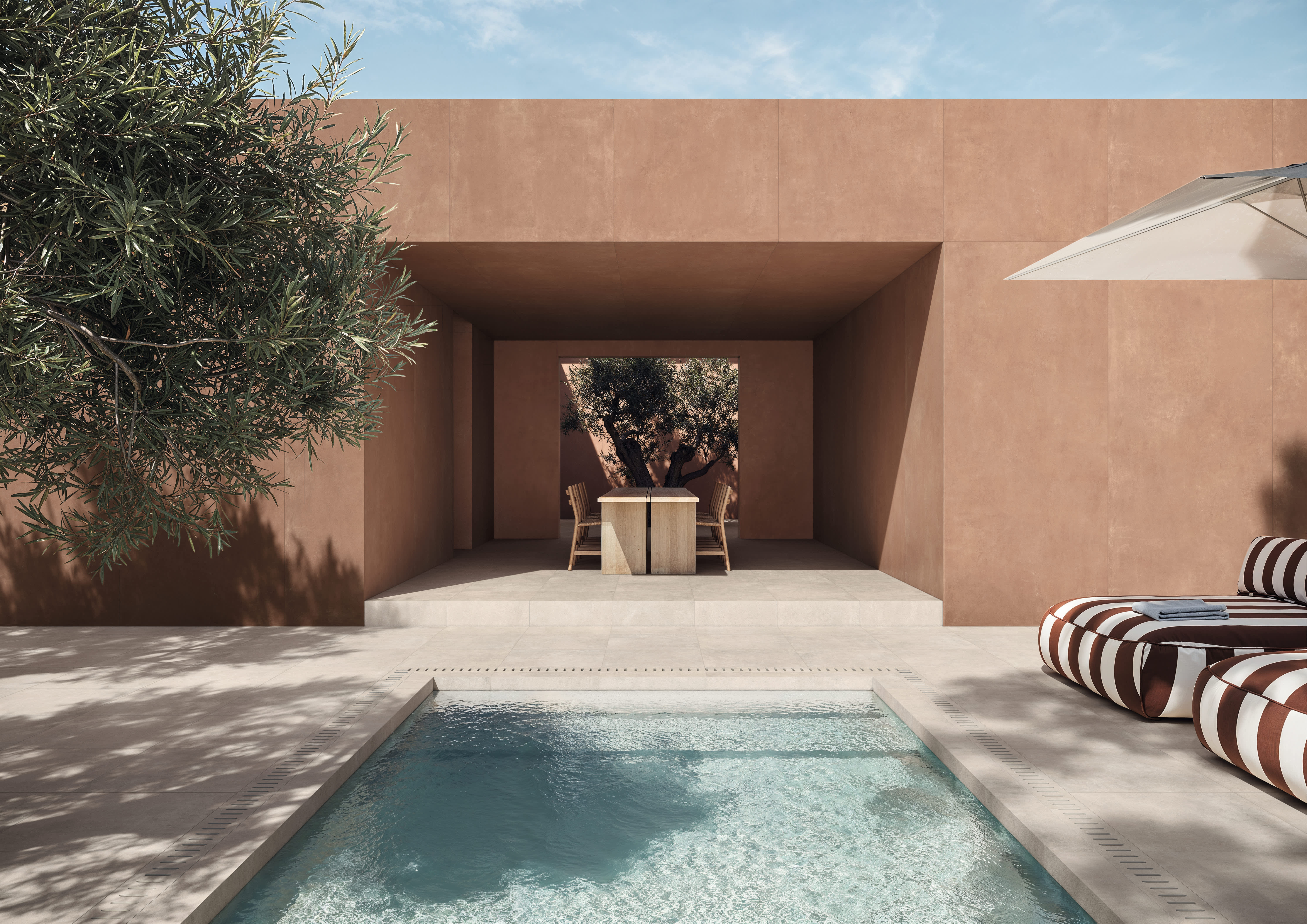 Concrete porcelain tile in Terracotta cladding a poolside pavilion, with Beige decking, striped loungers and a shaded dining nook.