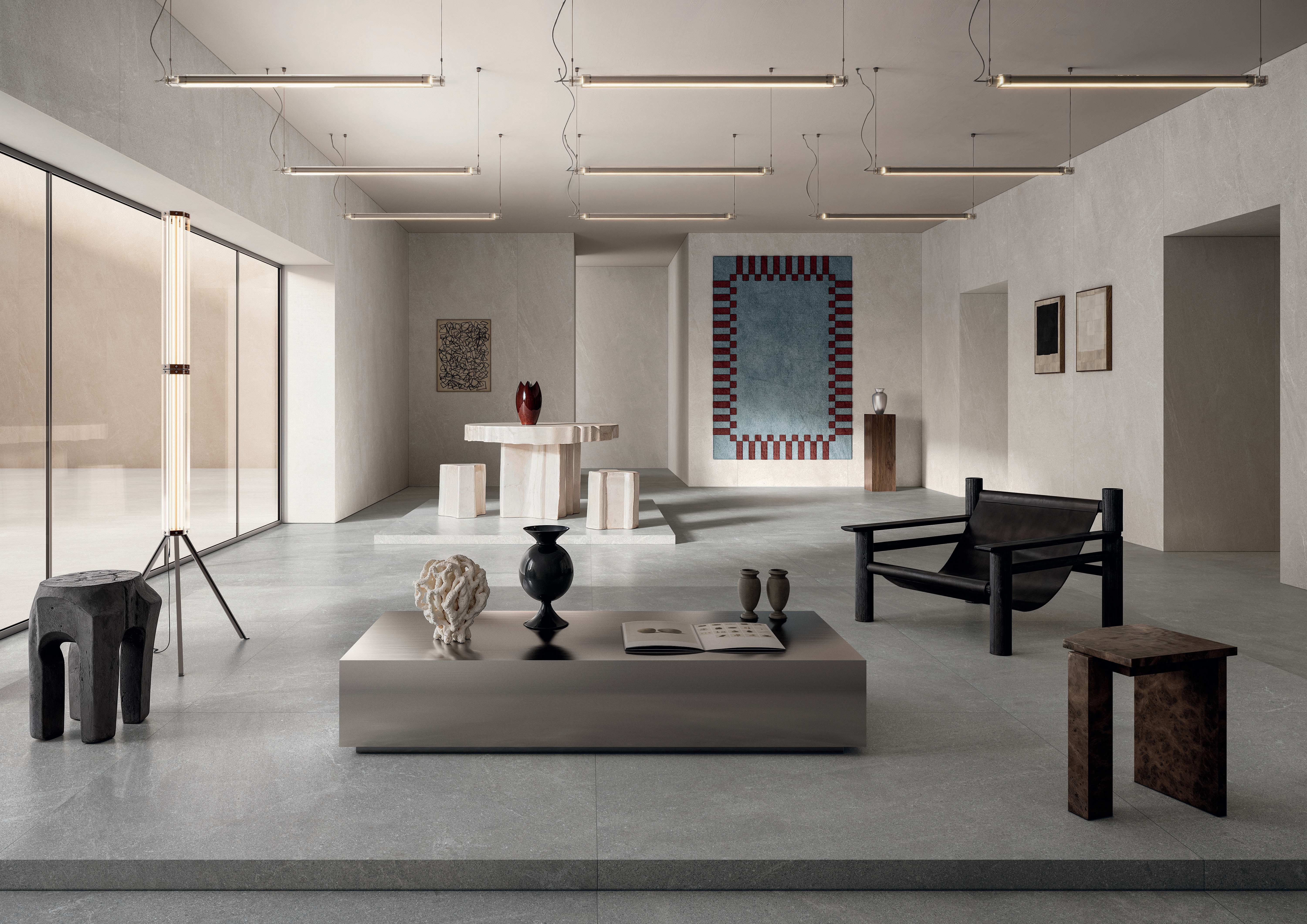 Gallery space in soft grey Mega Natural porcelain with sculptural plinths, artwork and a low display table.