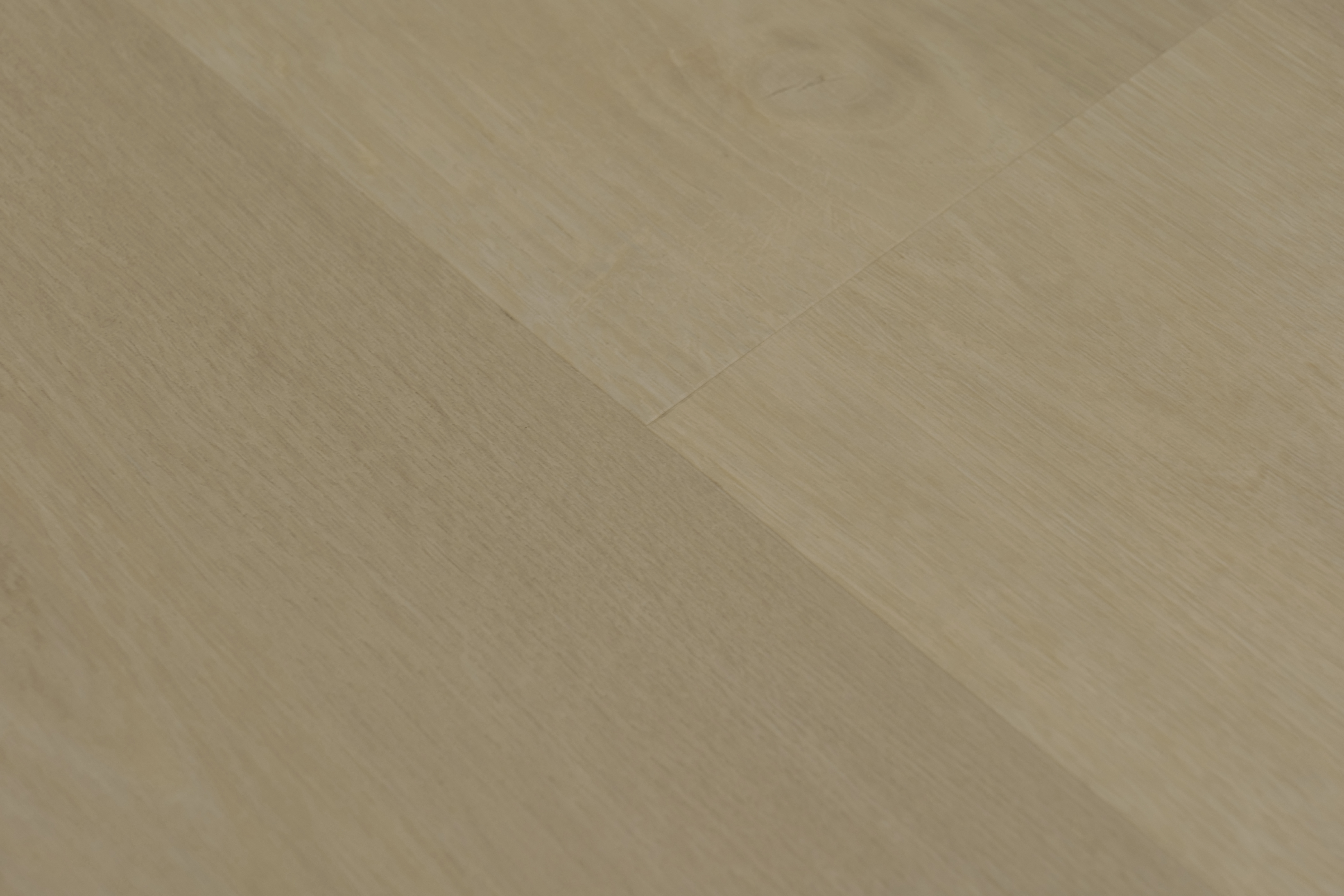 Close-up of Port vinyl flooring in Bow, showing a diagonal seam between pale beige wood-look planks with gentle grain
