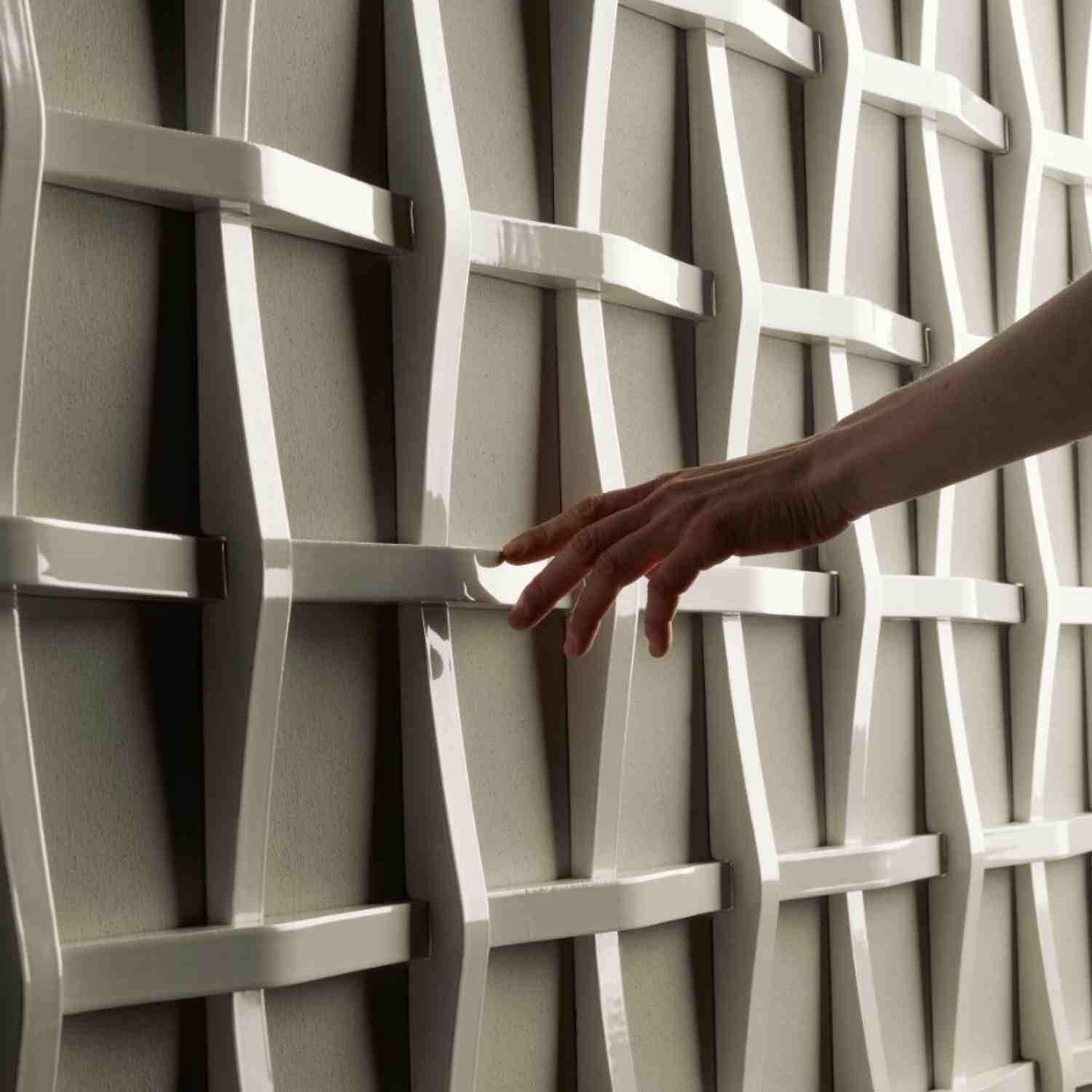 Mutina Adagio three-dimensional white ceramic wall tile with hand touching the sculptural woven lattice surface