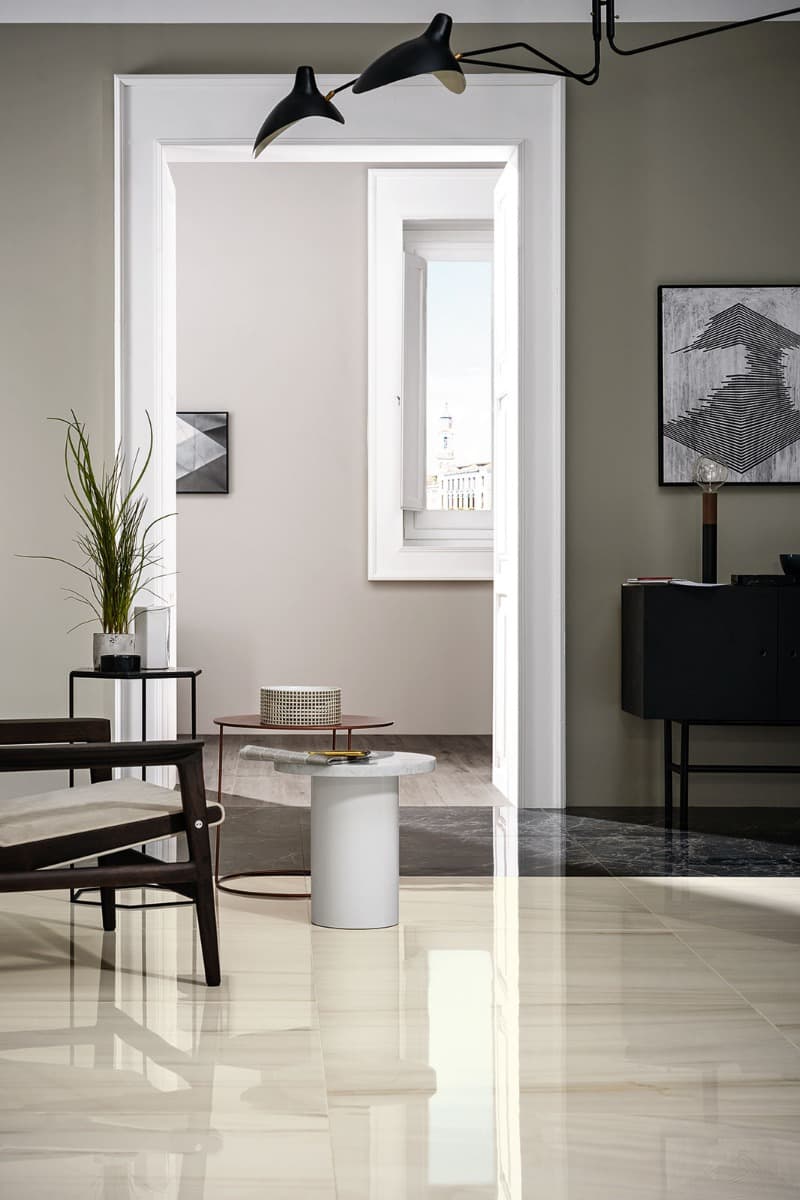 Marazzi All Marble mosaic Statuario porcelain stoneware door frame surround in elegant hallway with modern black sconce and contemporary decor