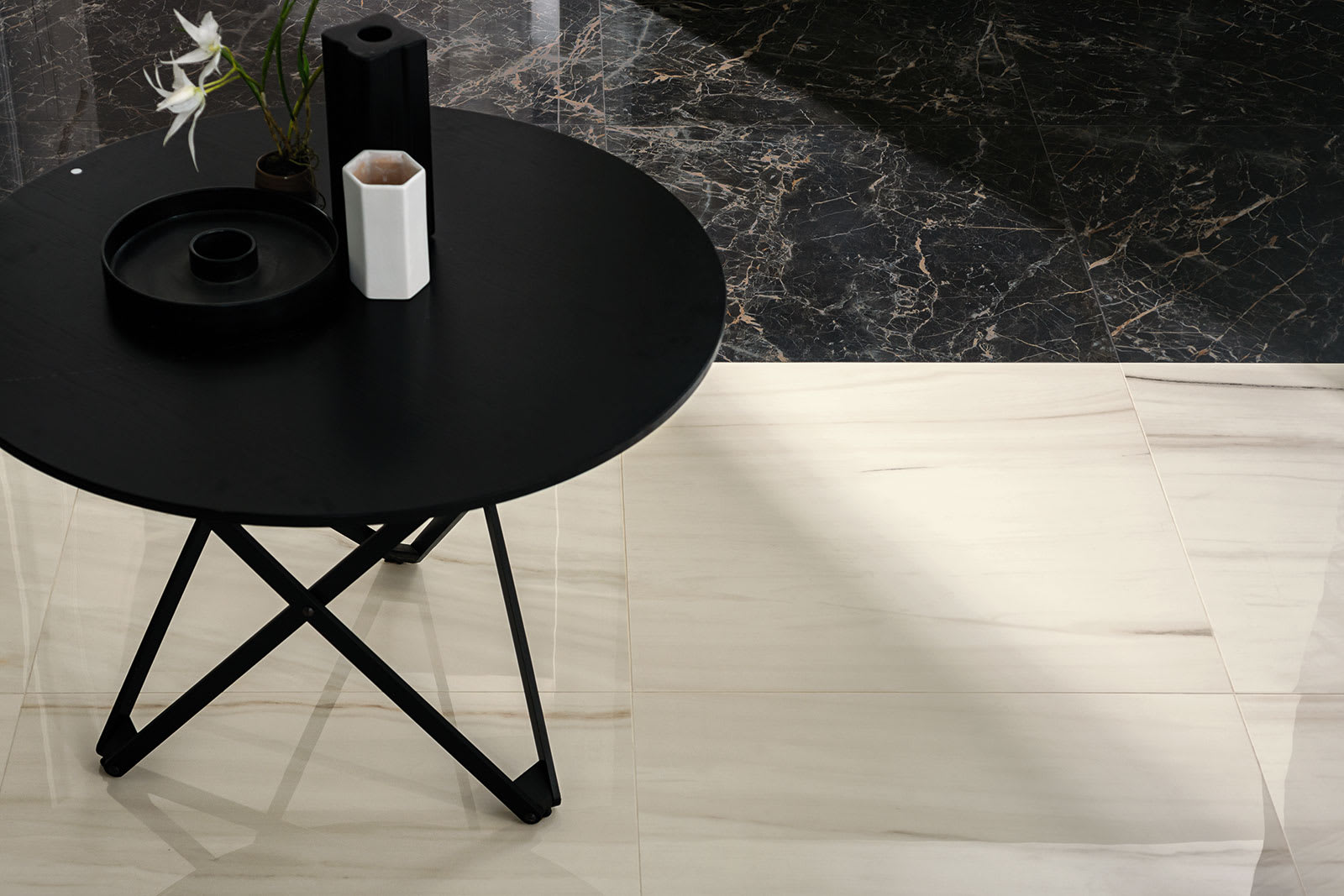 Marazzi All Marble mosaic Raffaelo dark marble-look porcelain wall with gold veining and Statuario white marble-look floor tiles black side table with white vase