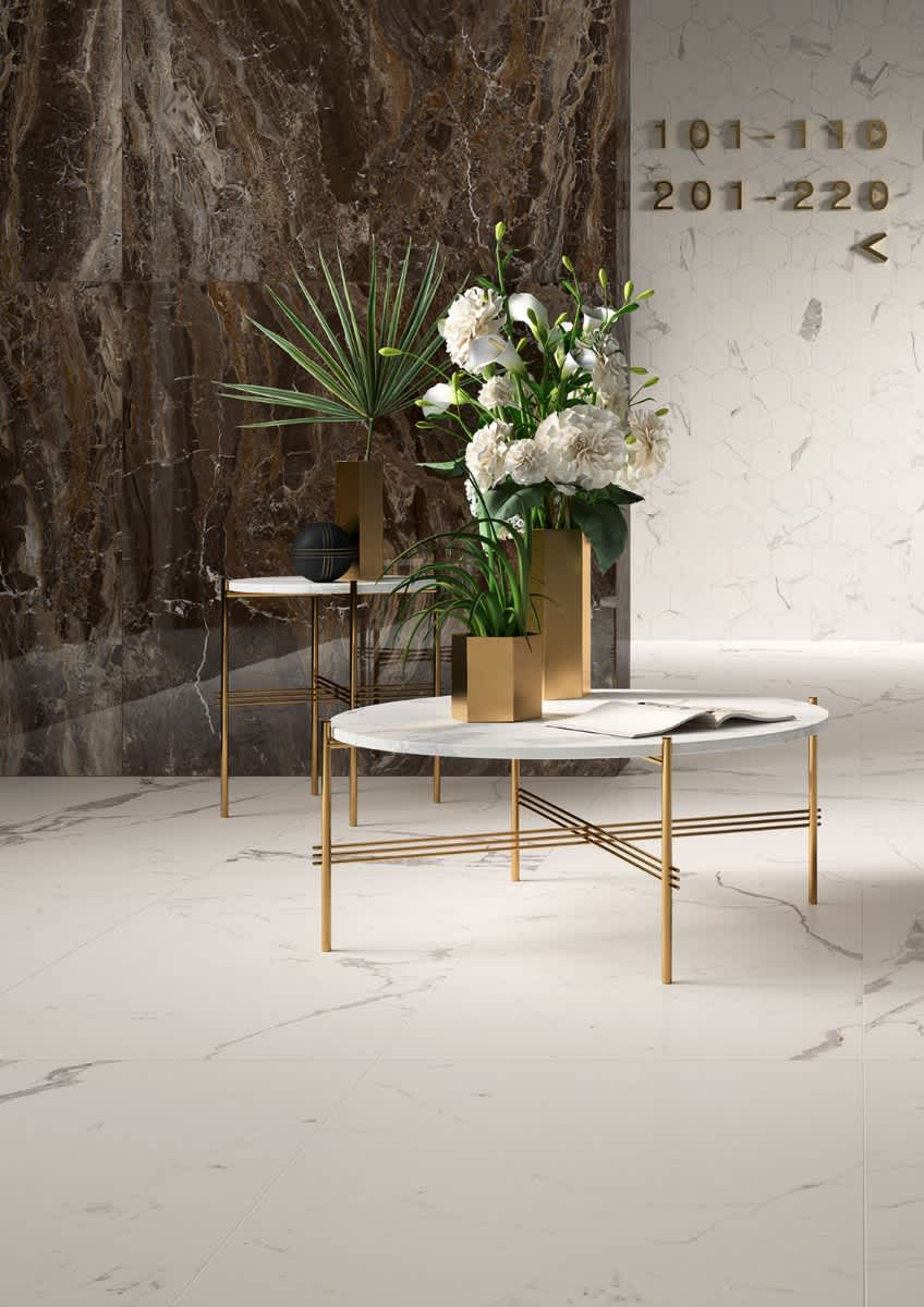 Marazzi All Marble mosaic Raffaelo and Statuario porcelain stoneware hotel lobby detail with dark marble wall room numbers gold coffee table white marble top and floral arrangement