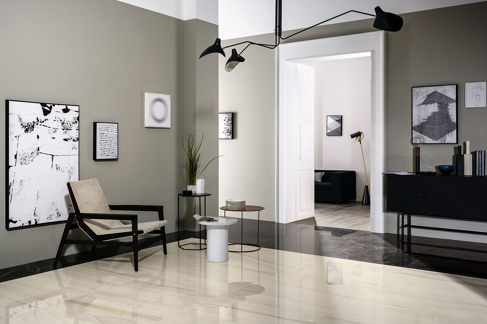 Marazzi All Marble mosaic Statuario and Raffaelo porcelain stoneware modern living space with white marble floor dark marble accent black armchair contemporary artwork and black chandelier