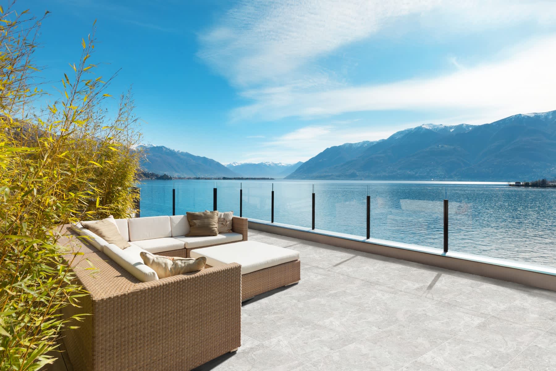 Max Glory Antalya glazed porcelain tile outdoor terrace with stone-look patio tiles wicker sectional sofa lake and mountain panoramic view and glass railing