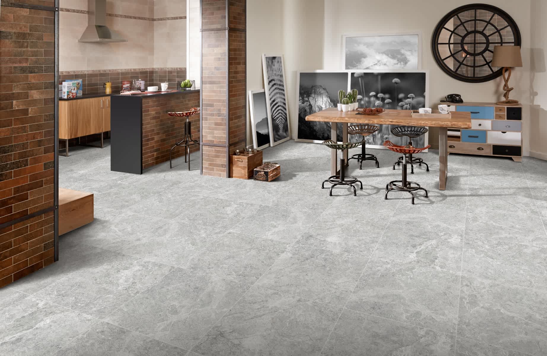Max Glory Antalya Grey glazed porcelain tile industrial kitchen dining space with stone-look floor tiles brick accent wall wooden table industrial bar stools and open shelving
