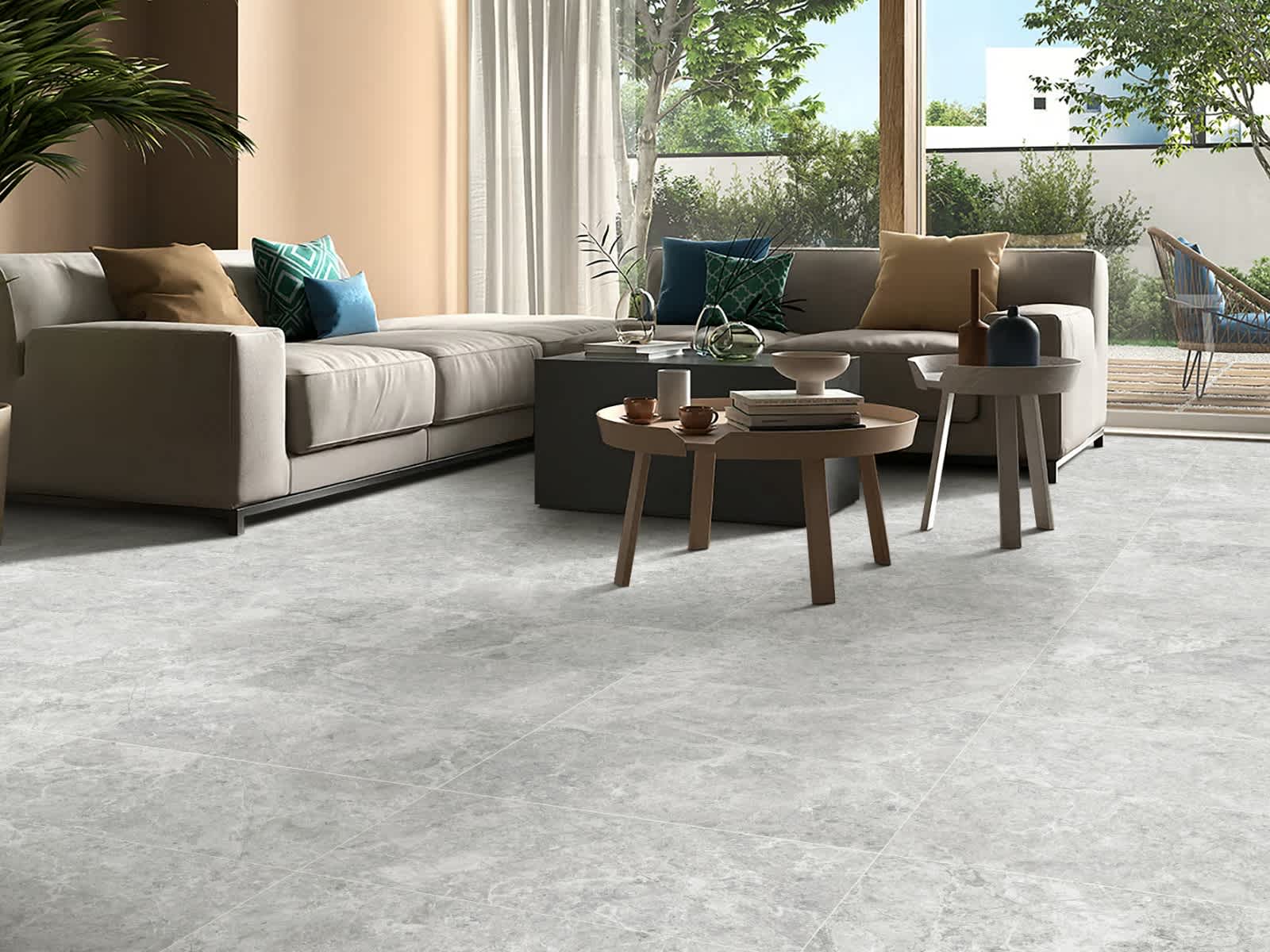 Max Glory Antalya Bianco glazed porcelain tile living room with light stone-look floor cream sectional sofa teal accent pillows round wooden coffee tables and garden terrace view