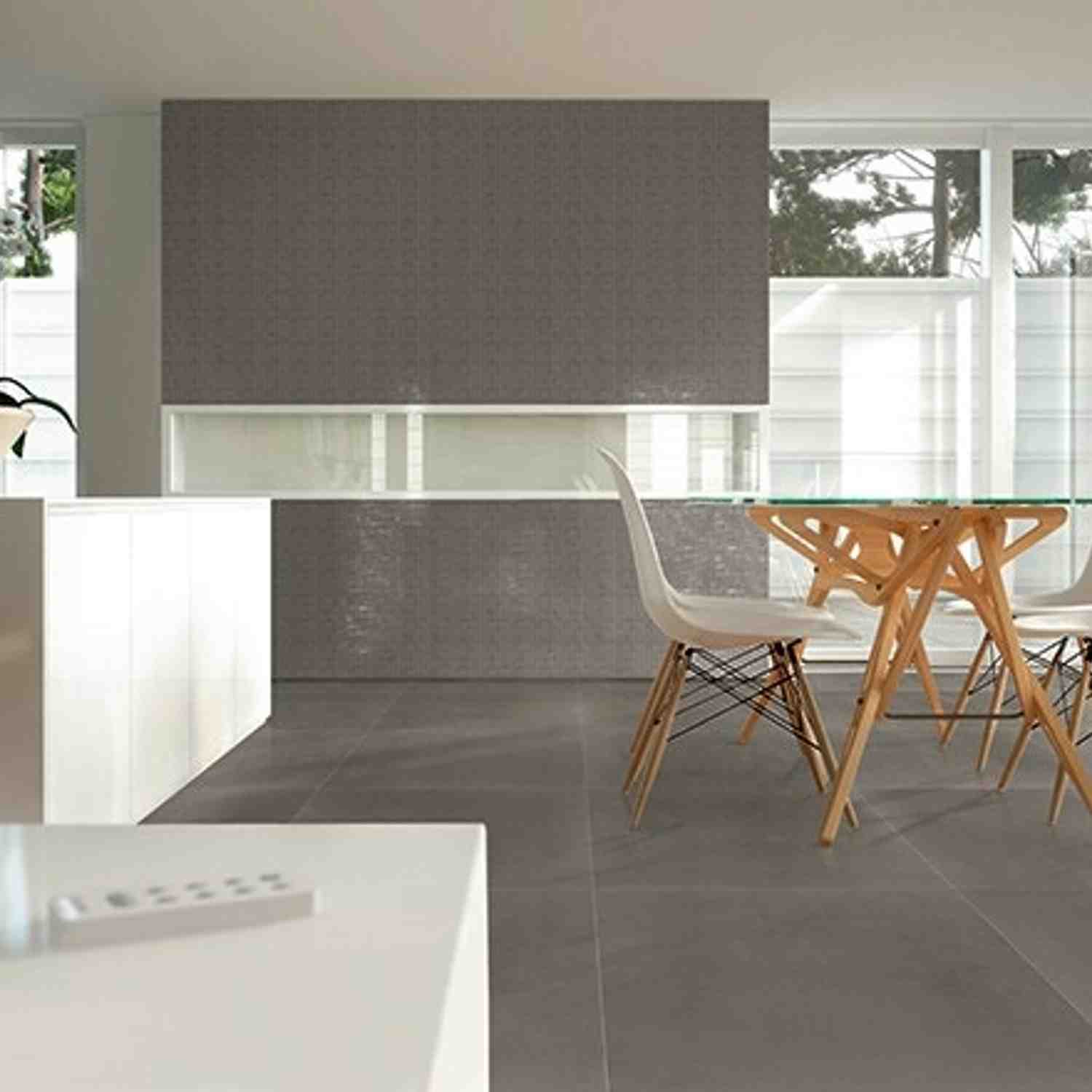 Terratinta Betontech Grey full-body porcelain stoneware wall and floor tile in open concept dining kitchen with white Eames chairs wooden table white counter and large windows