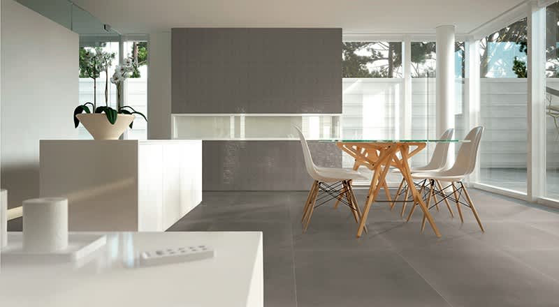 Terratinta Betontech mosaic Grey full-body porcelain stoneware floor and wall tile in modern open concept dining kitchen with white Eames chairs and large windows