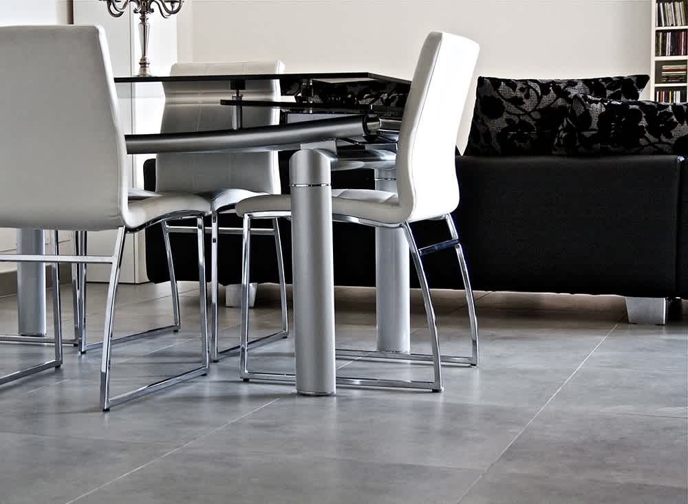 Terratinta Betontech mosaic Anthracite full-body porcelain stoneware floor tile in modern dining area with chrome and white leather chairs glass table and dark sofa