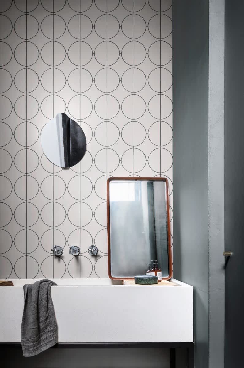 Cementum decorative cement-look porcelain tile with circular pattern installed as wall cladding with wall sconce and leaning mirror