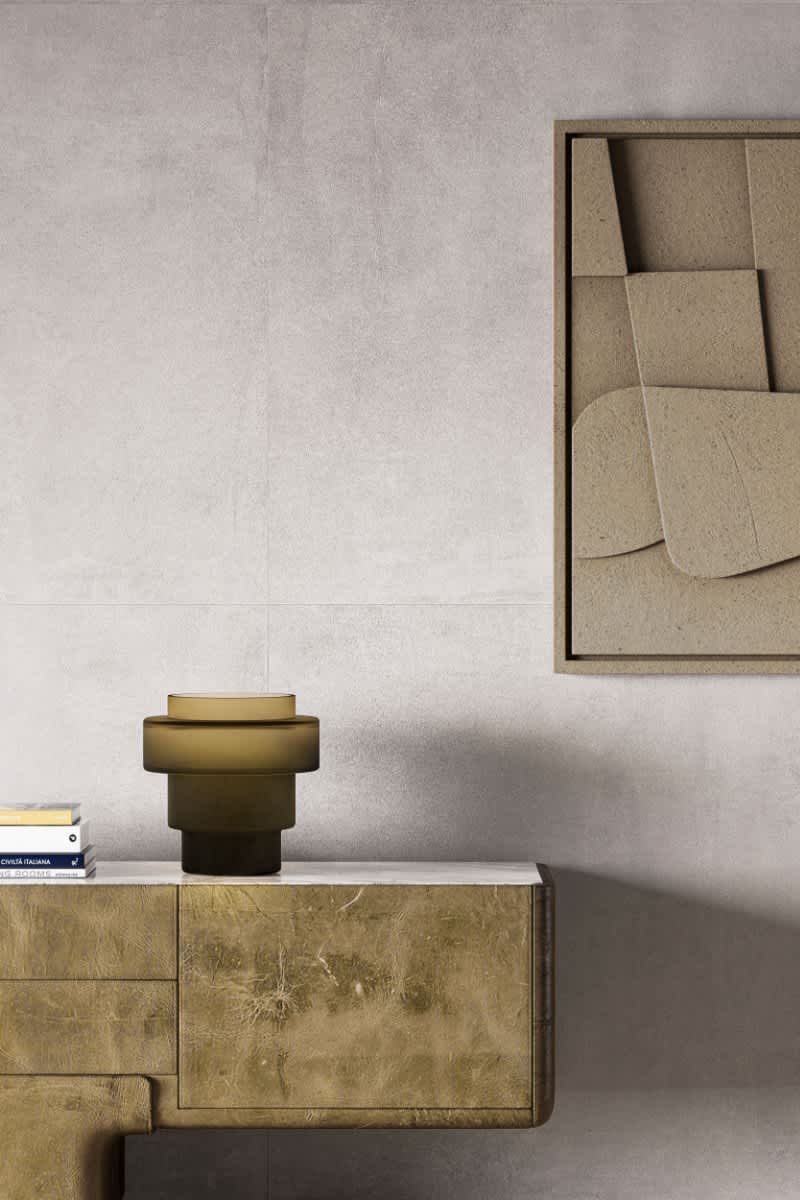 Cementum cement-look porcelain tile in light gray installed as wall cladding in a modern living space with beige sofa and gold side table