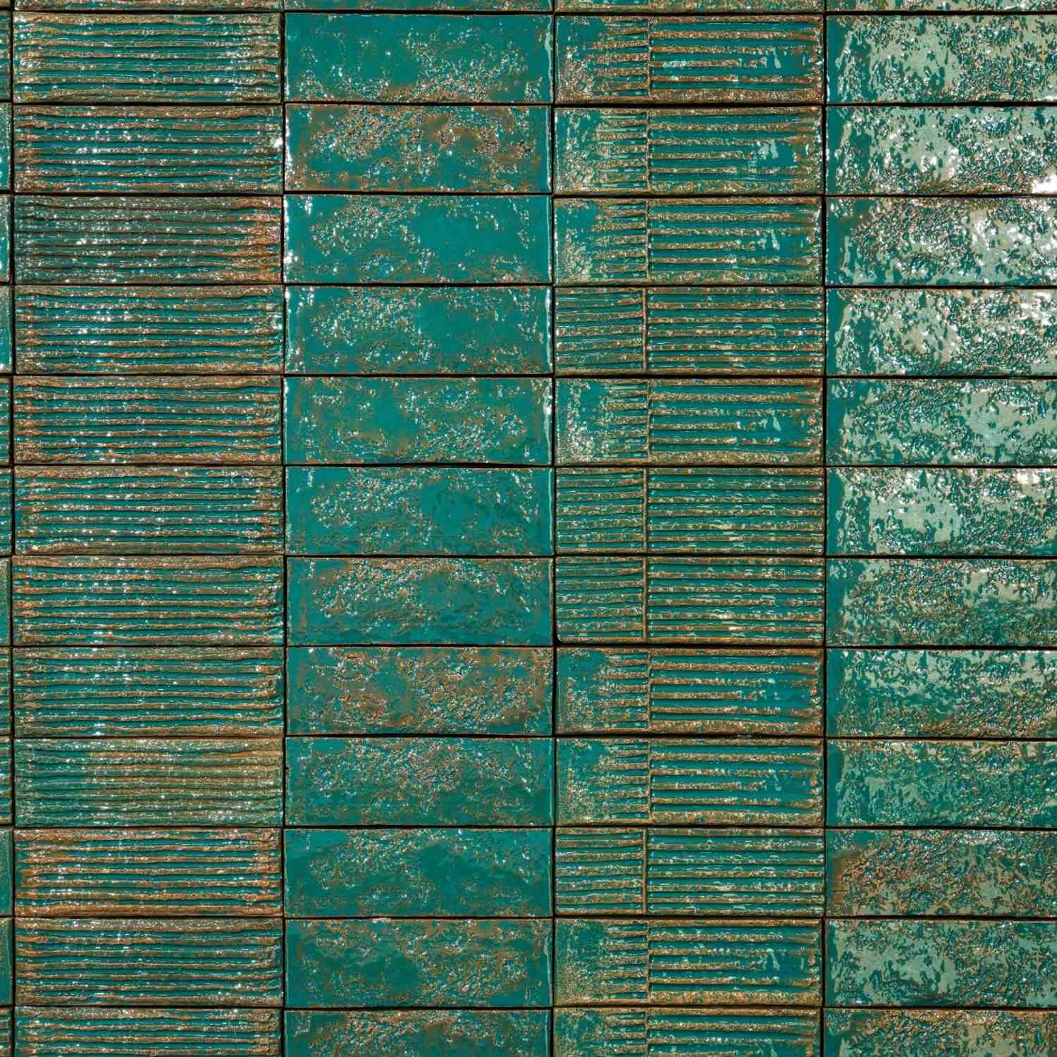 Mutina Chamotte Verde high-gloss glazed ceramic wall tiles installed showing mixed Linea and Mono patterns in rich teal-green with copper brown undertones and tactile relief texture
