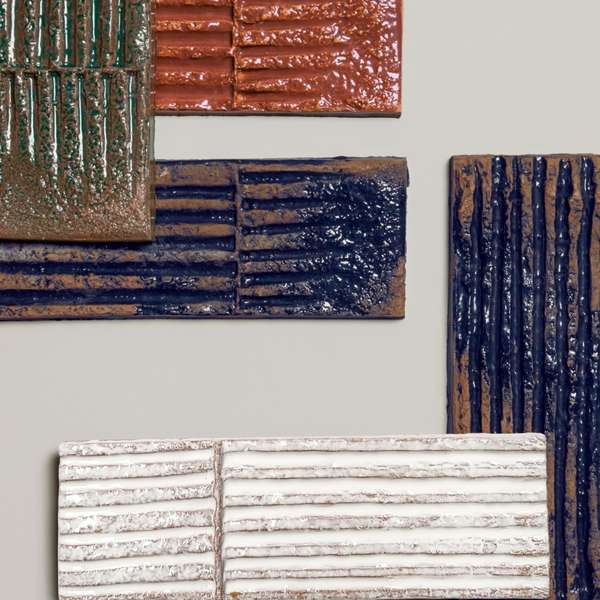 Mutina Chamotte high-gloss glazed ceramic wall tile samples showing multiple colors and textures including Verde green Terra brown Nero dark blue and Bianco white with tactile relief patterns