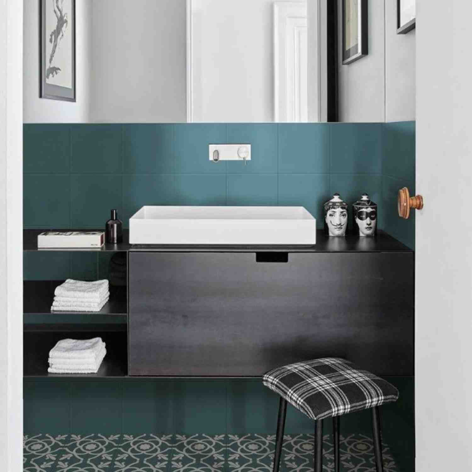 Marazzi Contrasti glazed porcelain stoneware wall tiles in bold teal dark turquoise matte finish installed in bathroom with white rectangular vessel sink dark vanity wall-mounted faucet decorative ceramic face vases and framed artwork