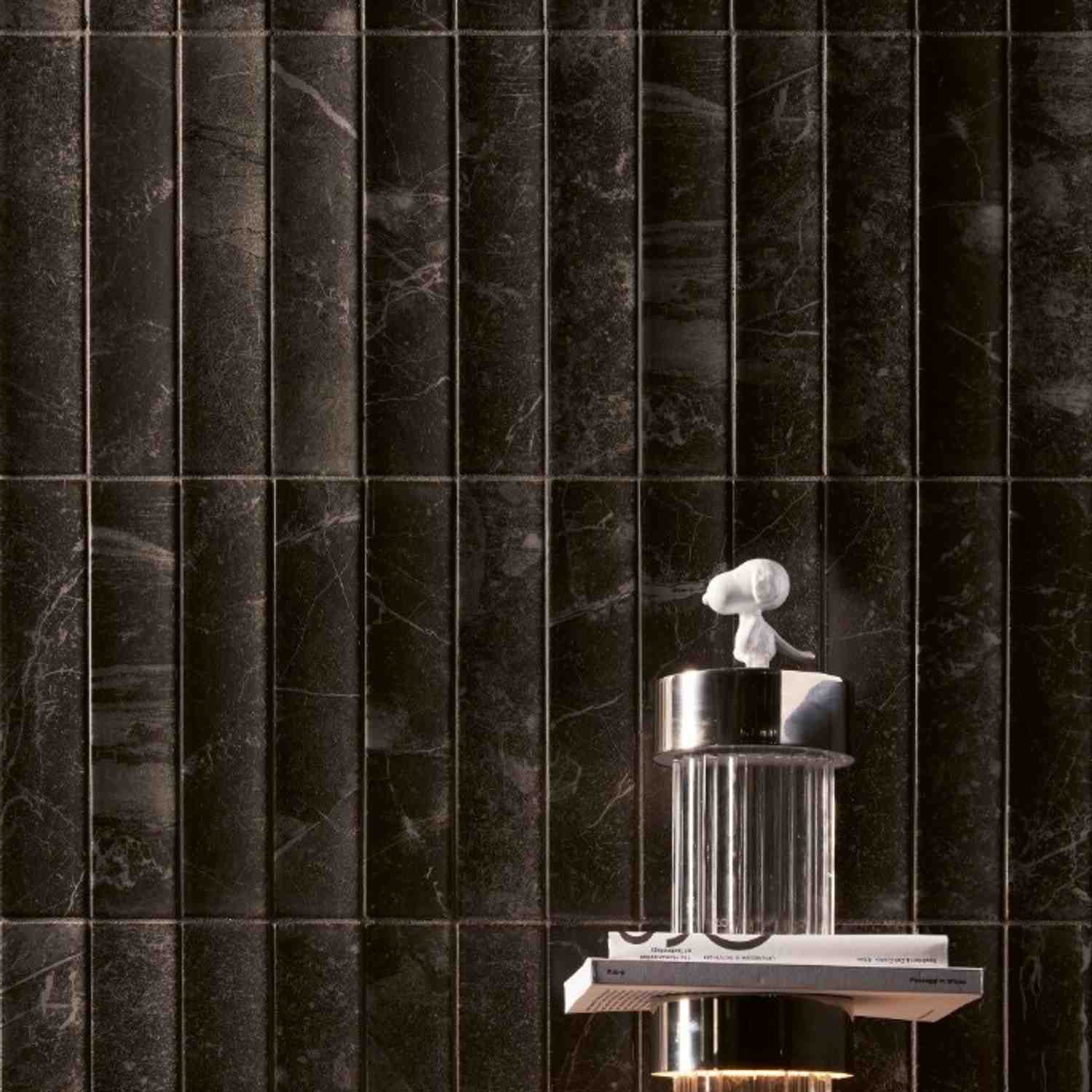 41zero42 Dandy glazed porcelain stoneware dark green black marble-look vertical strip wall tiles with white veining and white abstract decorative sculpture on chrome pedestal stand