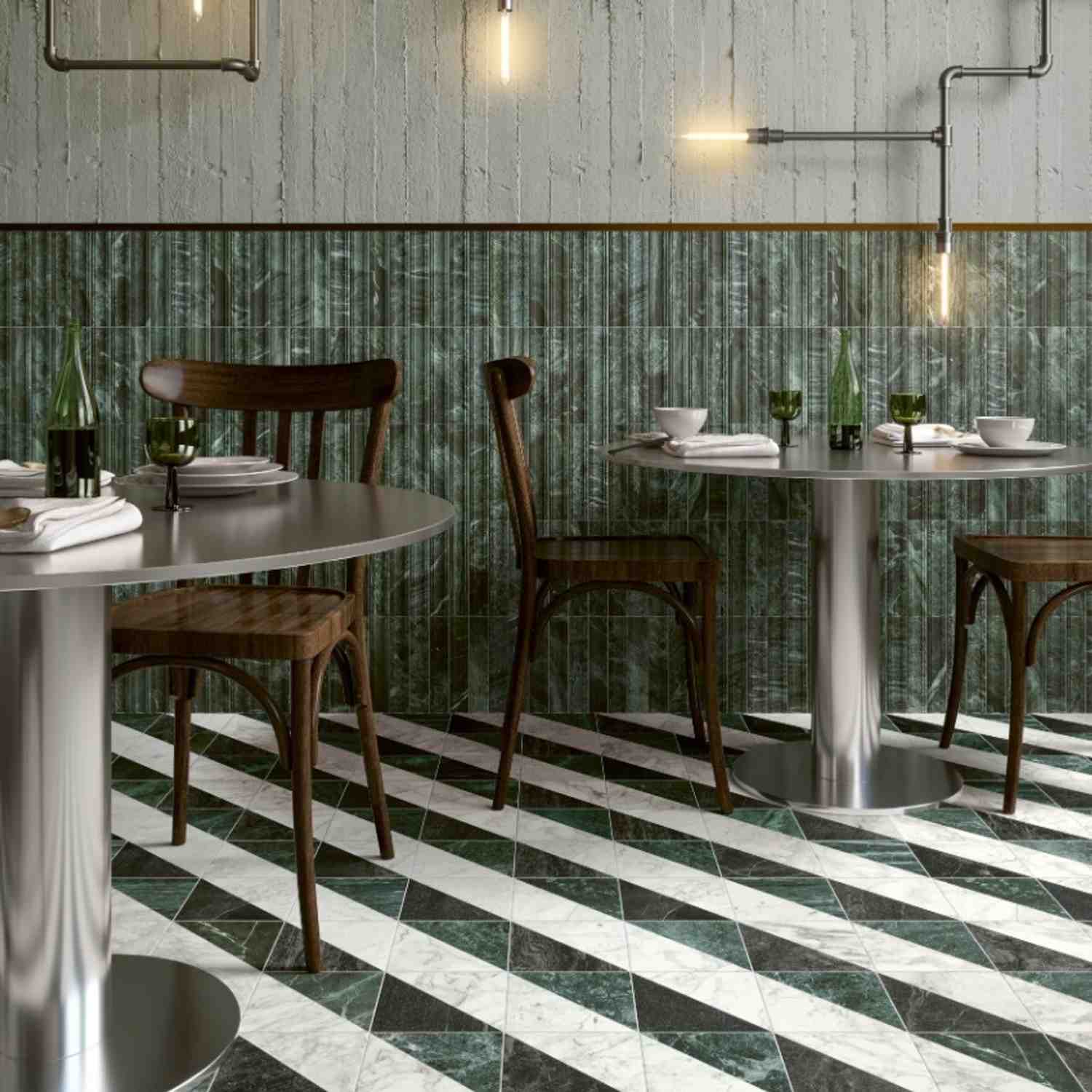 41zero42 Dandy glazed porcelain stoneware dark green vertical strip wall tiles in restaurant cafe interior with industrial pipe wall lighting wooden bistro chairs round tables set with plates cups green glassware and black and white chevron floor tiles