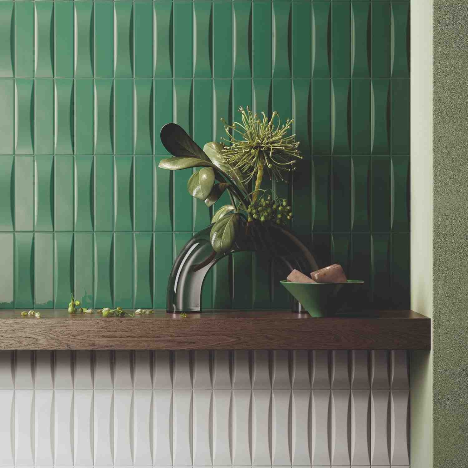 Elios Dust matte chevron ceramic wall tiles in ink dark emerald green with wave relief pattern showing three-dimensional surface texture with dramatic tropical floral arrangement in dark vase and pink ceramic bowl on shelf