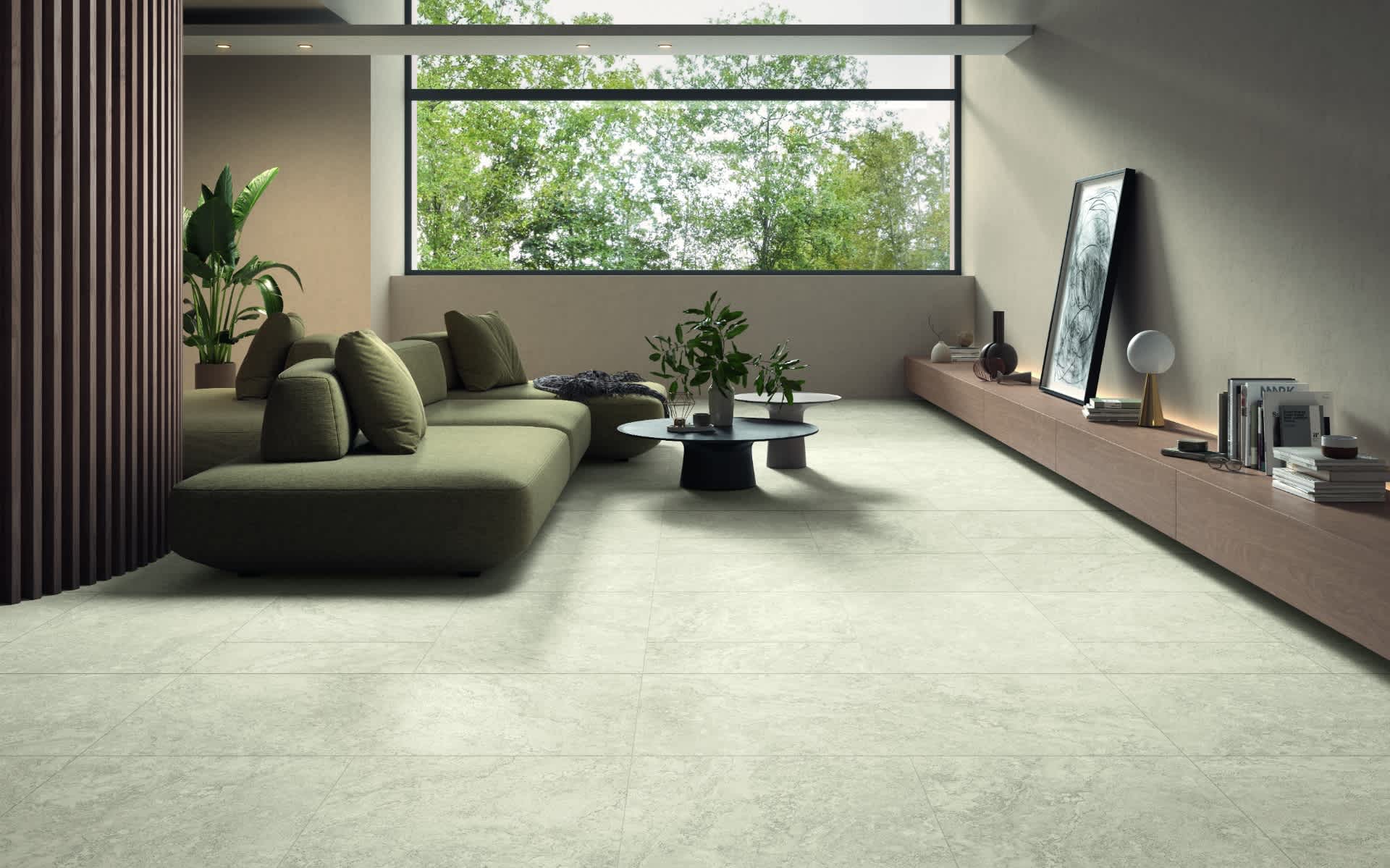 Castelvetro Firenze vein cut porcelain stoneware large format floor tiles in avorio cream installed in contemporary living room with olive green sectional sofa round black coffee table wooden media console framed artwork indoor plants and panoramic garden