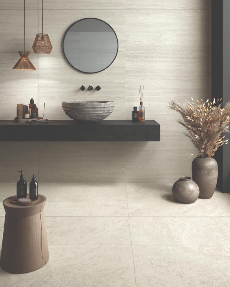 Castelvetro Firenze vein cut porcelain stoneware wall tiles in bianco light beige installed in modern bathroom with round black-framed mirror rattan pendant lights floating dark vanity stone vessel basin reed diffuser bathroom accessories and dried pampas