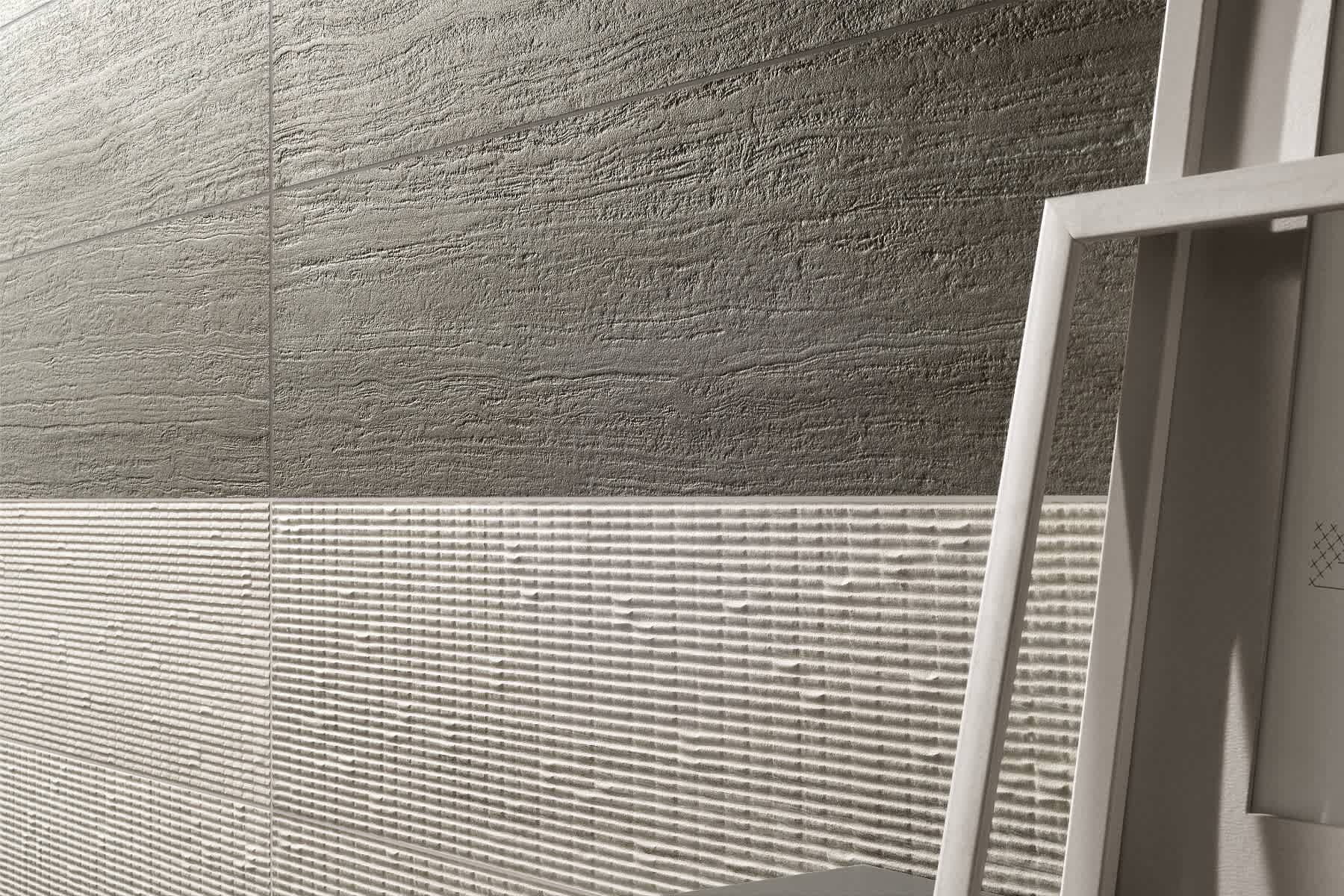 Coem Flow mosaic porcelain stoneware wall tiles showing two textured finishes with rough stone surface in dark grey and horizontal ribbed striation in light grey displayed with white picture frame accent