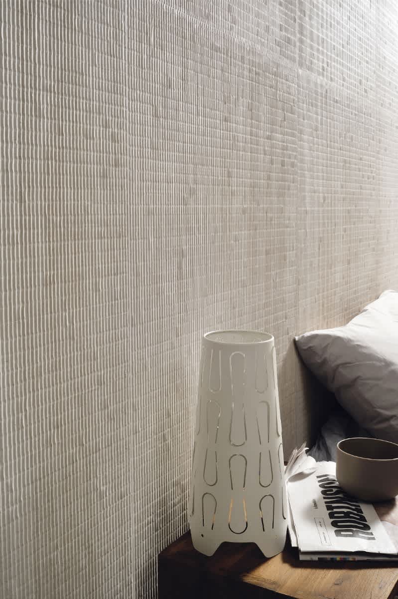 Coem Flow mosaic porcelain stoneware wall tiles in ivory beige with fine horizontal corrugated ribbed texture installed in contemporary bedroom with white ceramic side table and neutral bedding