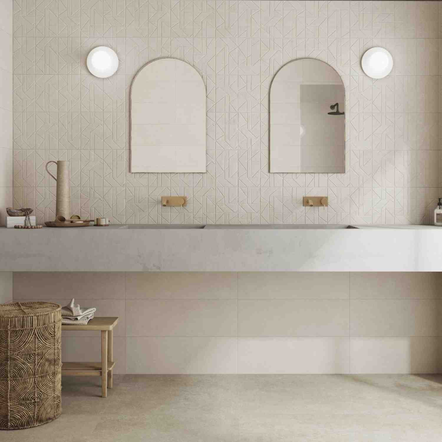 Argenta Gravel porcelain stoneware wall tiles in cream white with chevron herringbone textured pattern in elegant bathroom featuring arched mirrors round wall sconces brass wall-mounted faucets and marble countertop