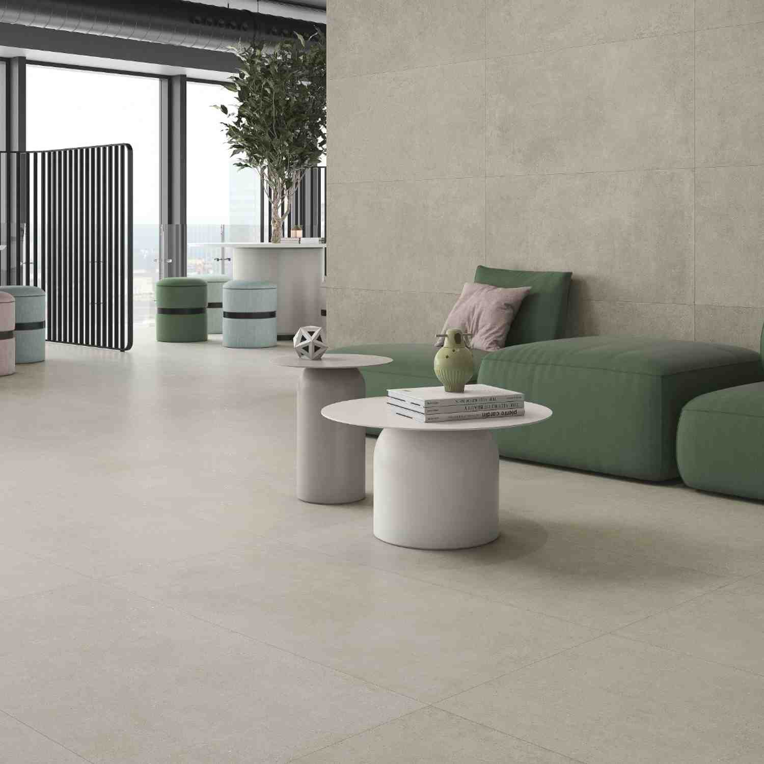Argenta Gravel porcelain stoneware wall and floor tiles in earth cream with stone-cement matte finish in modern open-plan living area with green sofa white coffee table black vertical slat divider and city view