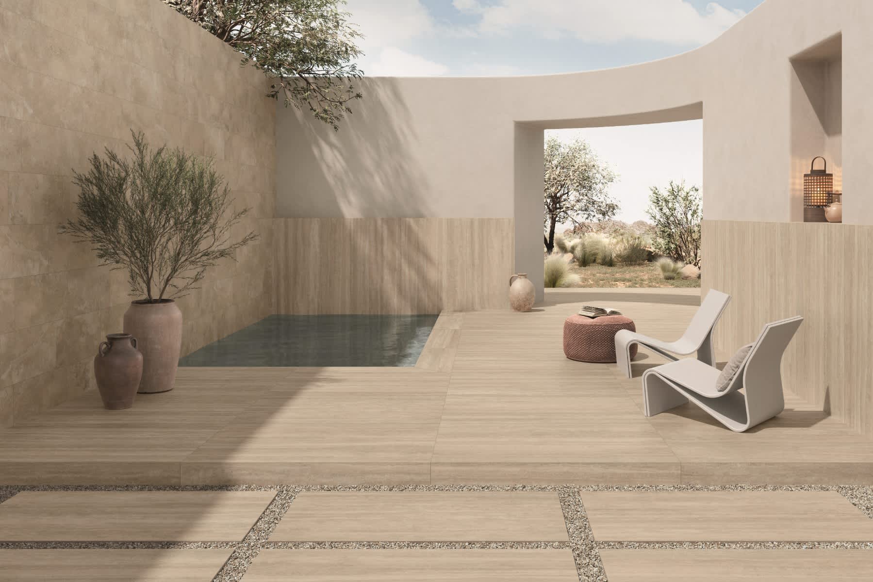 Caesar Iconica mosaic porcelain tile in warm beige Navona tone installed on outdoor terrace with dark plunge pool white lounge chair terracotta woven pouf olive trees clay vessels and desert landscape view