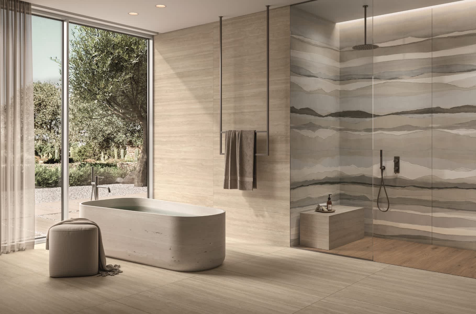 Caesar Iconica mosaic porcelain tile in luxury bathroom with warm beige Navona wall cladding and Classico Contro layered stone-pattern feature wall behind rainfall shower freestanding bathtub and garden view