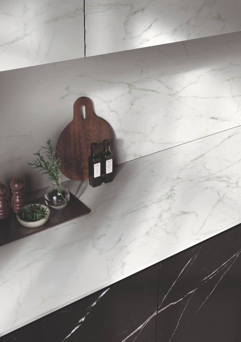 Italstone porcelain slab in Nero Marquina, used on the cabinet sides beneath a white marble counter and backsplash in a modern kitchen.