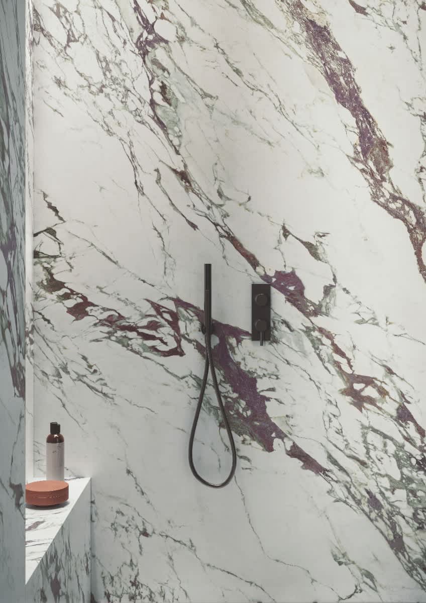 Italstone porcelain slab in Breccia Capraia, installed across a walk-in shower wall with bold violet and grey veining on white.