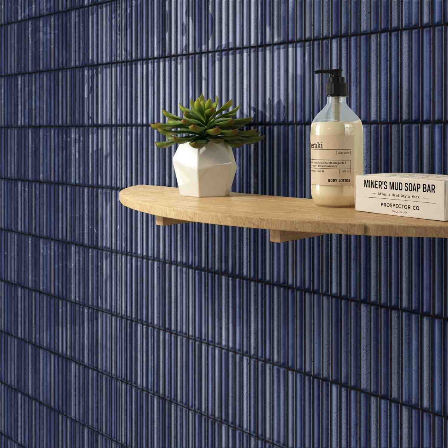 Estudio Ceramico Karatsu glazed porcelain wall tiles in midnight blue glossy finish with wooden floating shelf succulent plant in white vase and artisan bathroom products