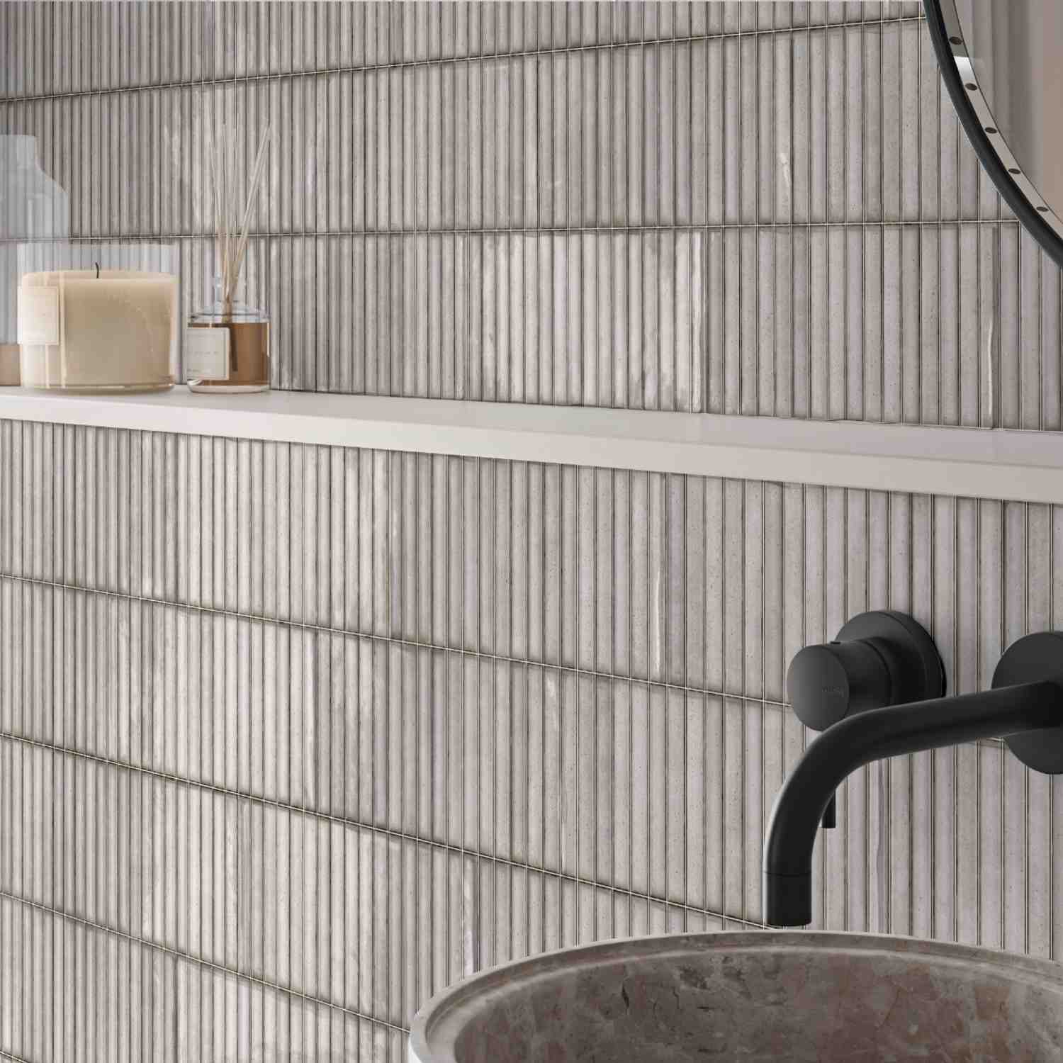 Estudio Ceramico Karatsu glazed porcelain wall tiles in chalky white grey horizontal linear pattern installed in bathroom with round mirror candle reed diffuser and black fixtures