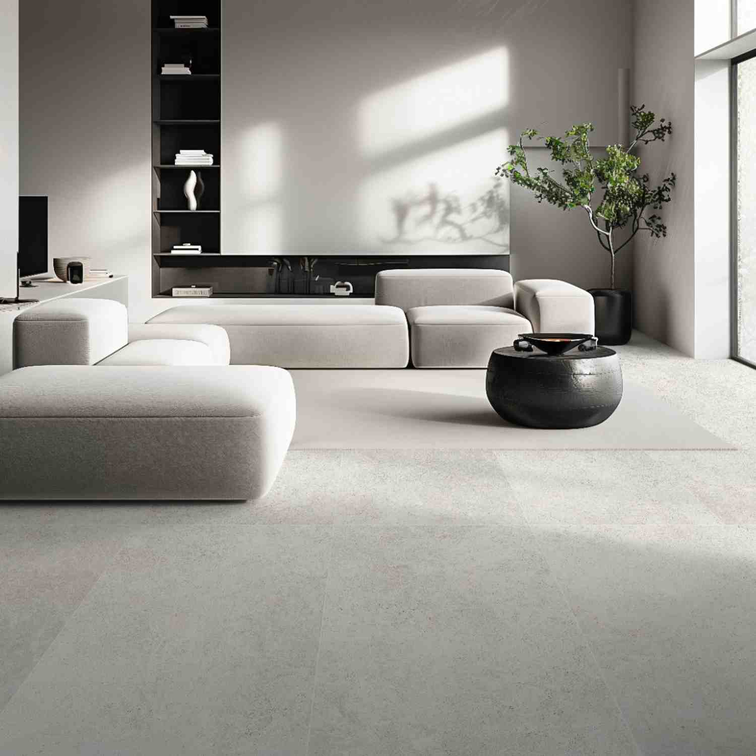 Overland Limestone light ivory porcelain floor tiles in modern living room with cream sectional sofa, black ceramic coffee table, dark built-in shelving, abstract wall art, and indoor greenery
