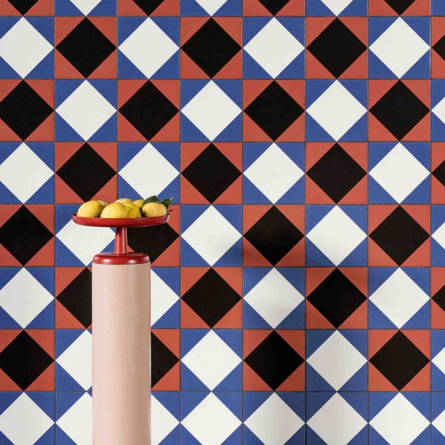 Mutina Margherita Rhombus graphic pattern wall tiles in terracotta, blue, black, and white diamond design with red cake stand and lemons as decorative styling