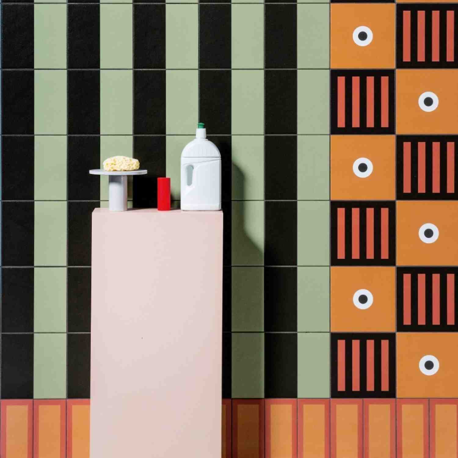 Mutina Margherita green and black Petals pattern wall tiles in bathroom setting with pink shelf and bath products alongside terracotta Point pattern accent tiles