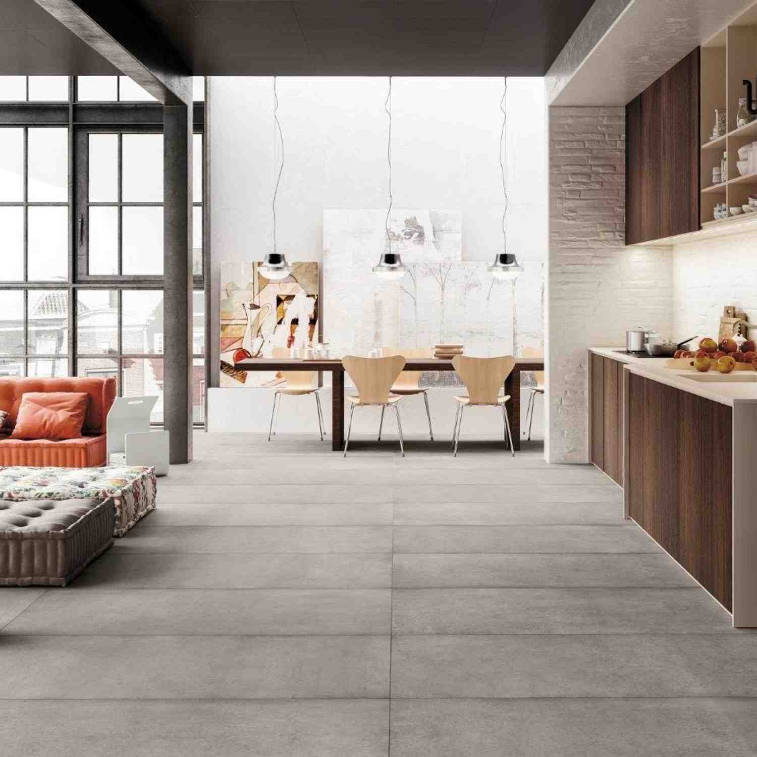 Refin Masterplan loft-style open living and dining space with light grey Mist porcelain floor tiles, industrial windows, pendant lights over dining table, orange accent sofa, walnut kitchen cabinetry