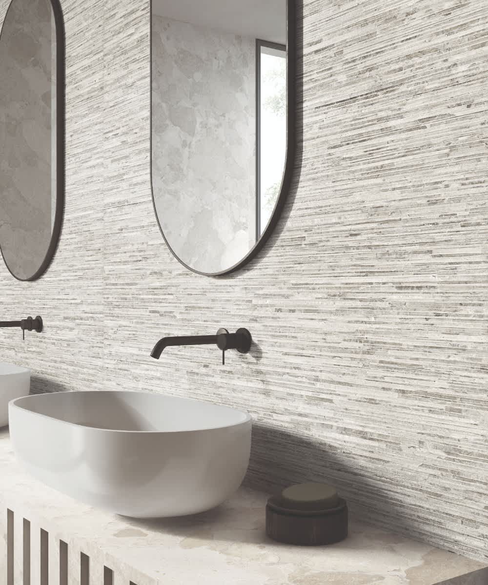 Ergon Materastone Ritmo Greige porcelain stoneware wall tiles with horizontal linear texture in a bathroom with dual oval mirrors and wall-mounted matte black faucets