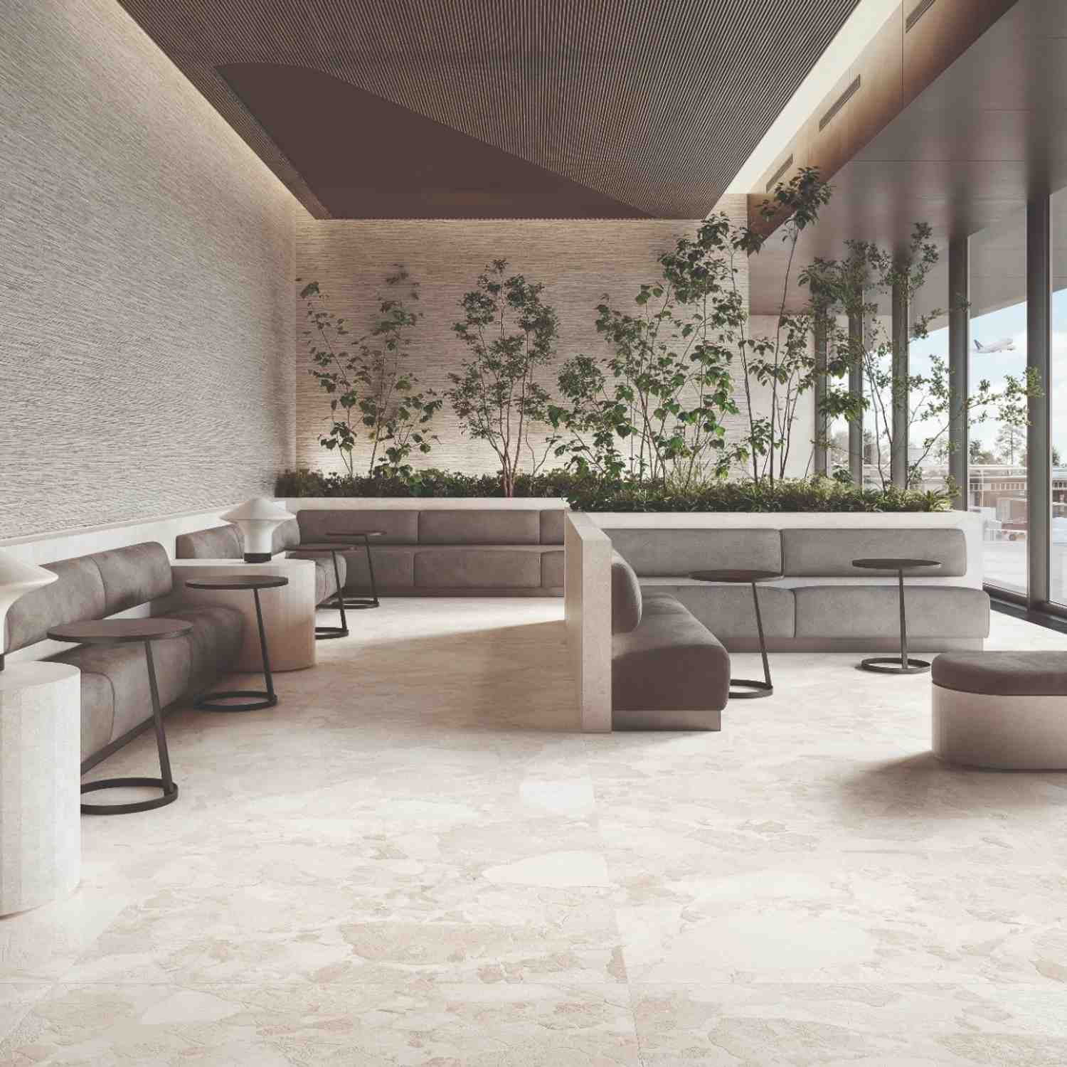 Ergon Matera Stone beige porcelain wall tiles in modern outdoor lounge terrace with grey modular seating, indoor trees, slatted wood ceiling and garden views