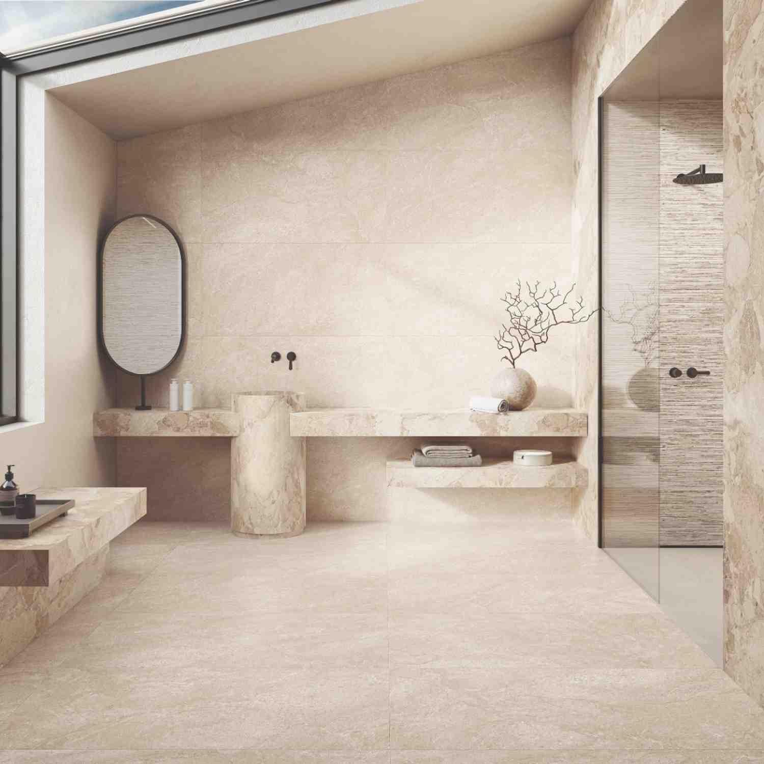 Ergon Matera Stone Beige porcelain bathroom with dual vessel sinks on floating stone vanity, oval mirror, black wall-mounted faucets, Ritmo accent strip, skylight
