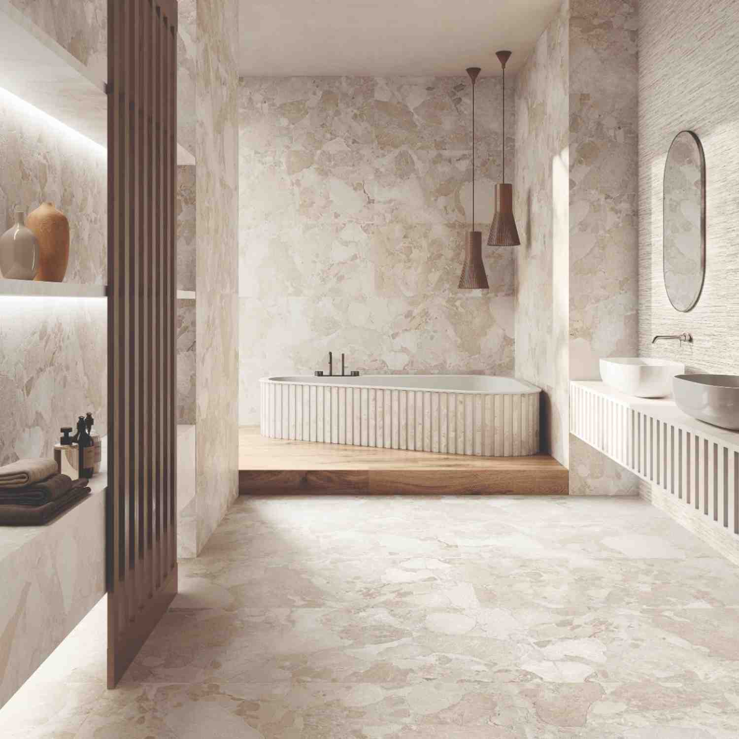 Ergon Materastone Sassi Beige porcelain stoneware walls in a luxury bathroom with fluted freestanding bathtub on wooden platform, dark conical pendant lights, oval mirror, and vessel sink vanity