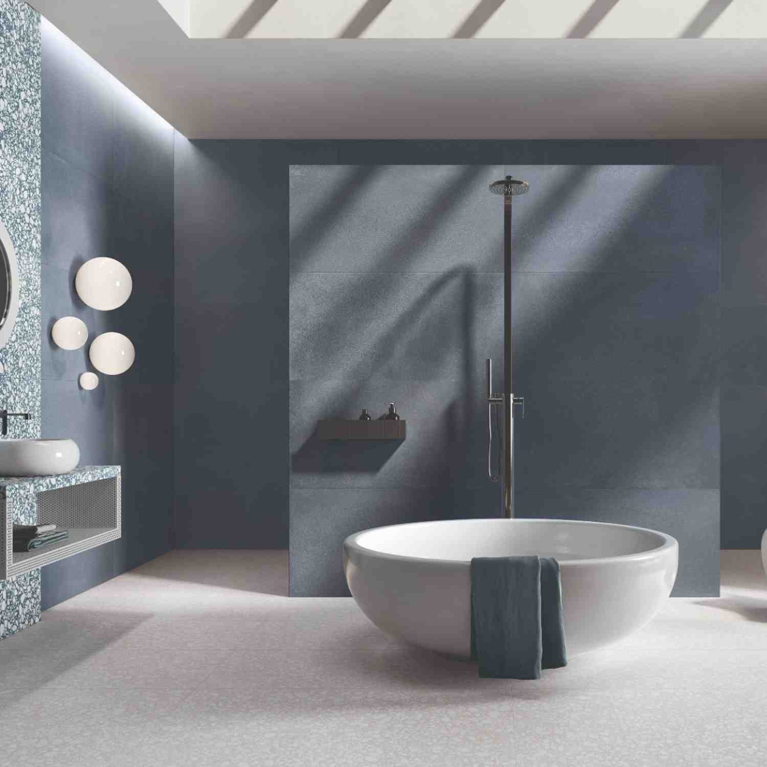 Emilceramica Medley Blue Minimal matte porcelain wall tiles in a spa-like bathroom with rain shower, brass fixtures, round bubble wall sconces, floating wooden shelf, and white freestanding bathtub
