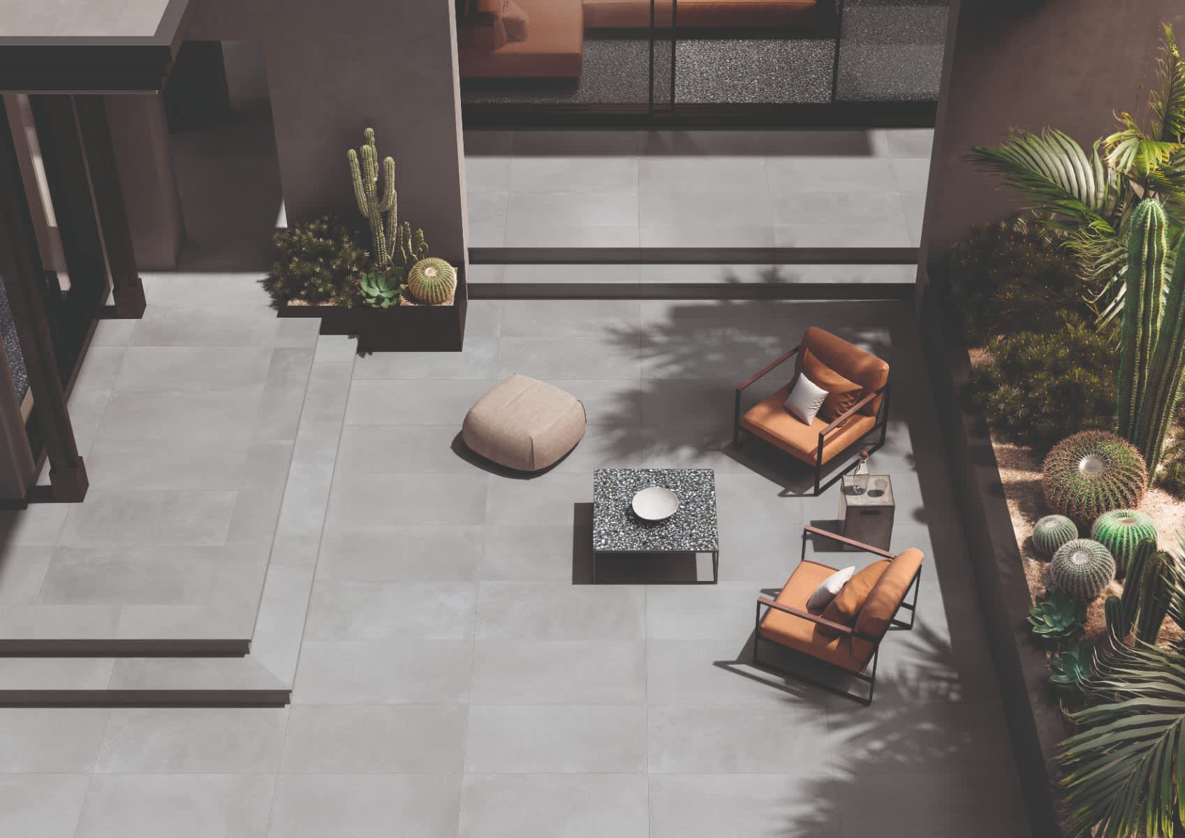 Emilceramica Medley Grey Minimal matte porcelain outdoor patio tiles seen from above with leather lounge chairs, fabric pouf, cacti planters, and terrazzo mosaic accent details