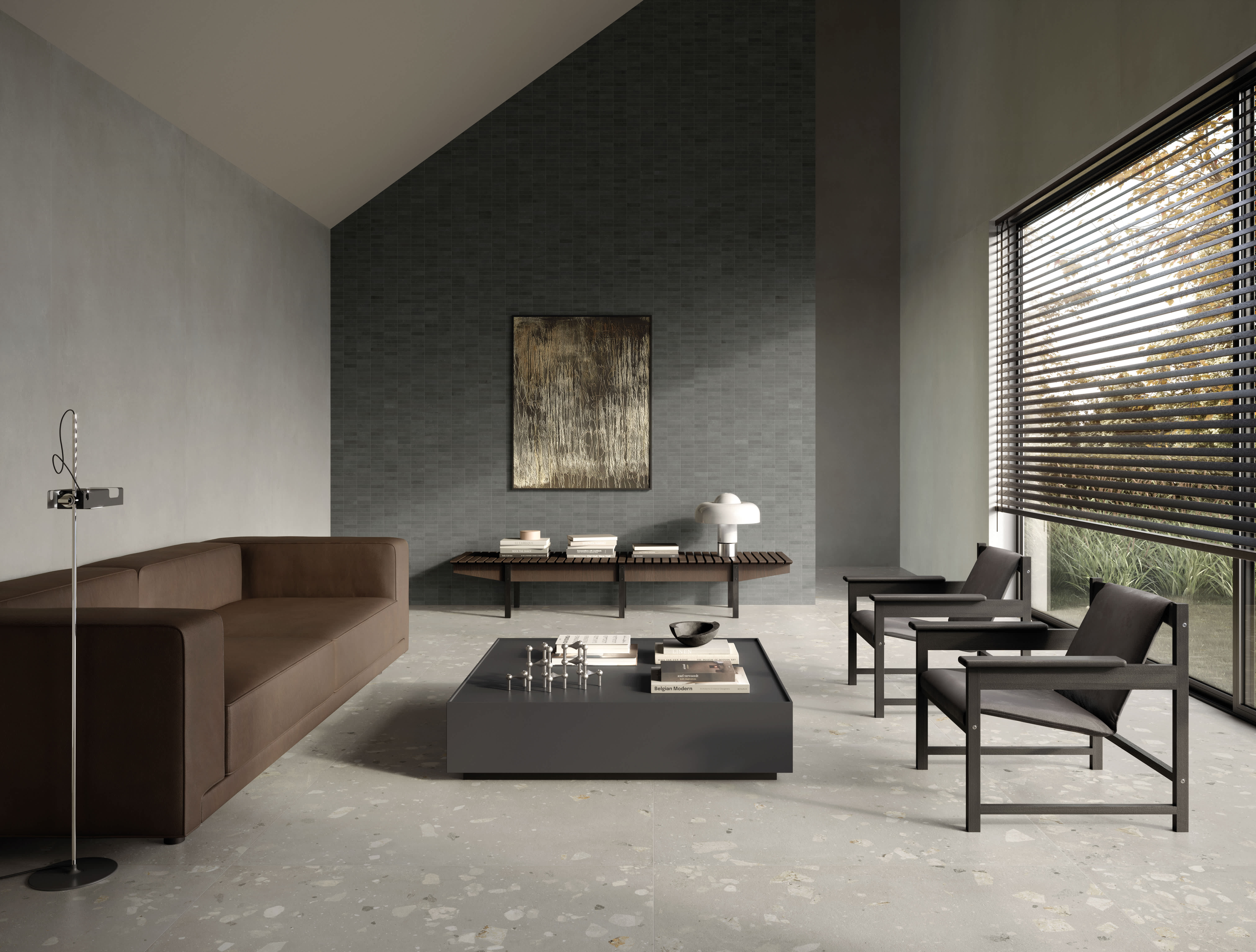 Living room with grey I Cementi porcelain slab walls, a charcoal brick-pattern mosaic feature wall, leather sofa and terrazzo-style floor.