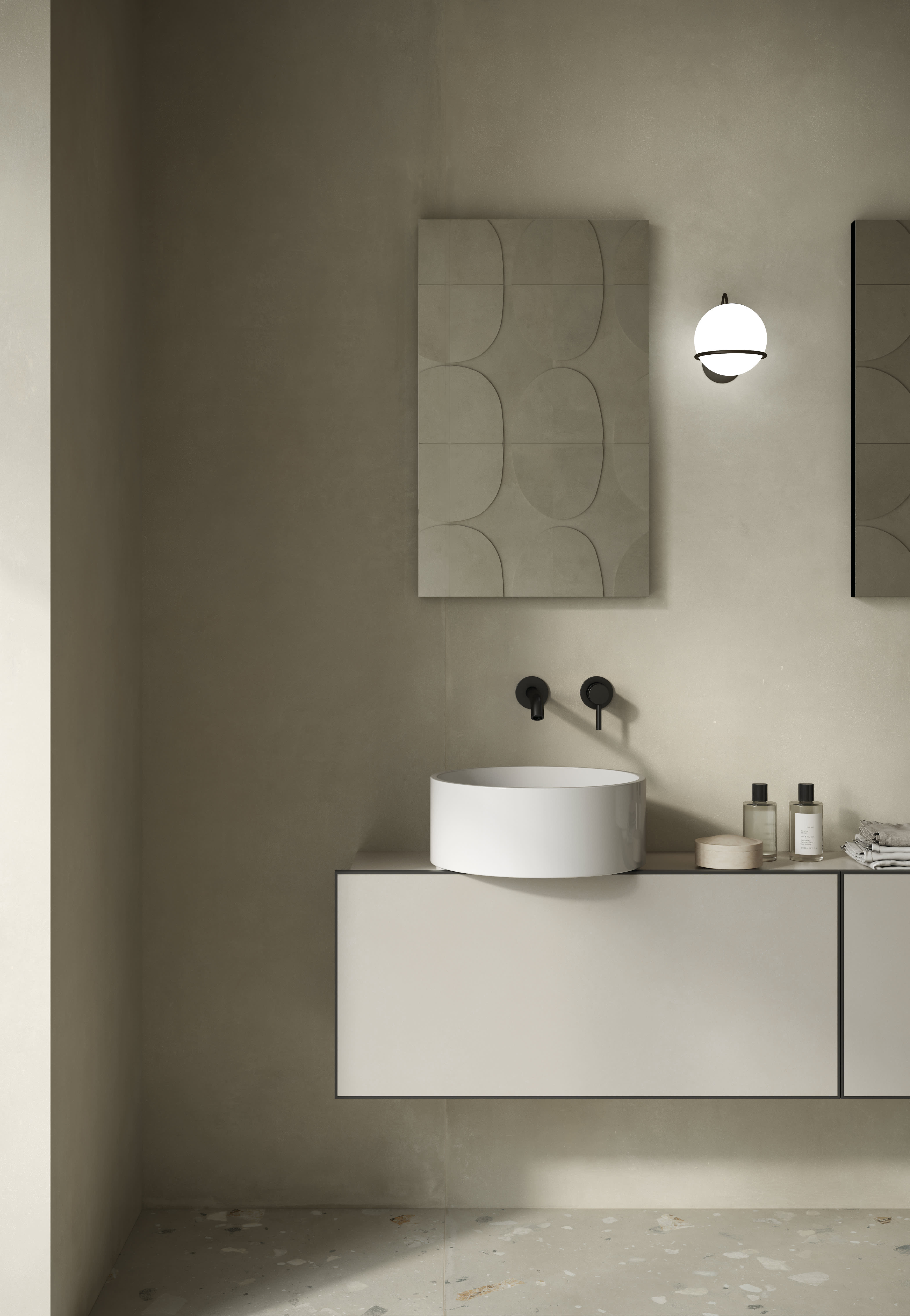 Bathroom wall in muted flax I Cementi porcelain slab with a round white basin, globe light and sculpted relief panel.