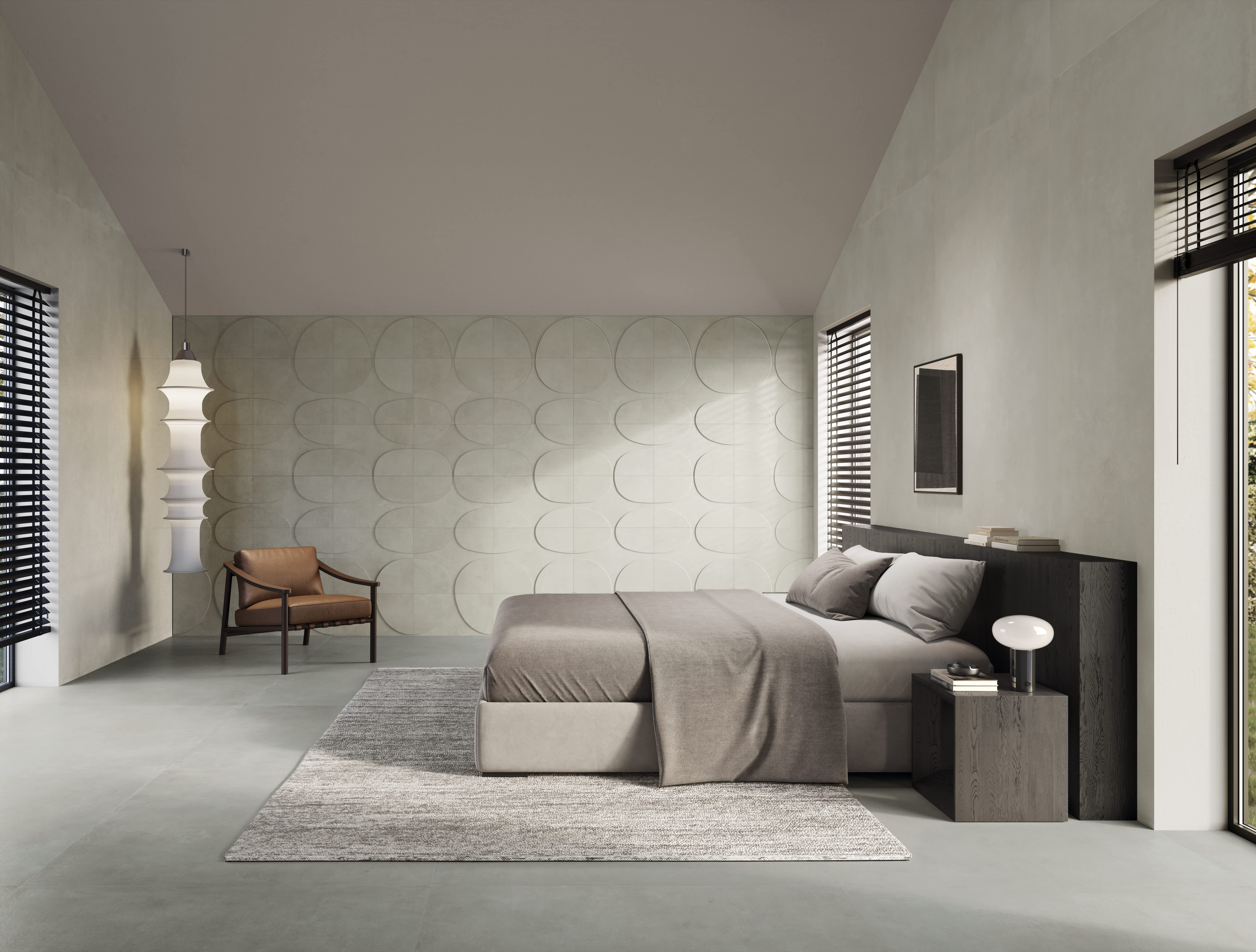 Bedroom in soft greige I Cementi porcelain slab with a sculpted relief feature wall, low bed, lounge chair and slatted blinds.