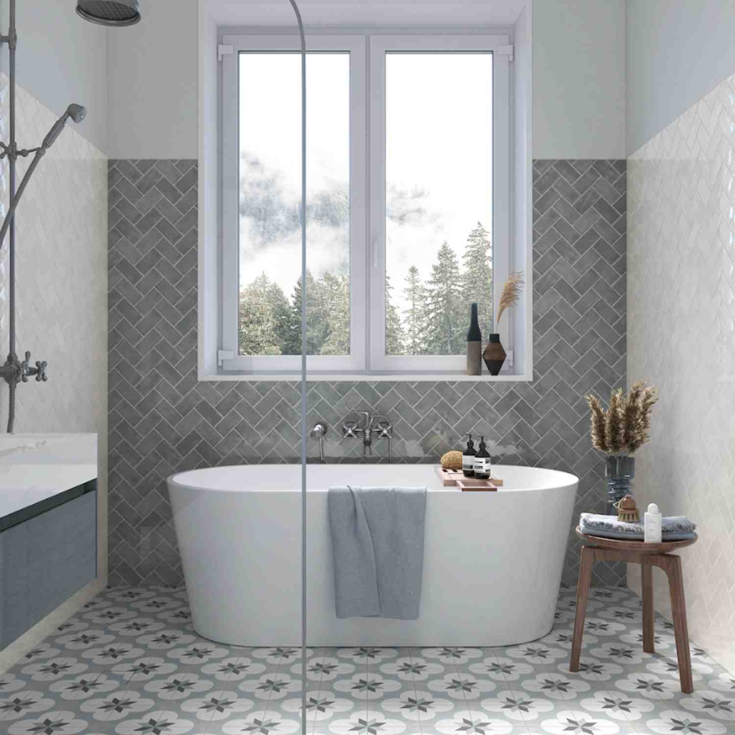 Terratinta Memorie grey herringbone pattern glossy ceramic wall tiles in a luxury bathroom with freestanding white bathtub, black rain shower, and forest view window