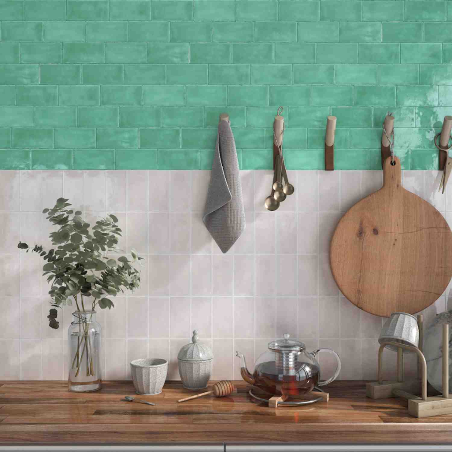 Terratinta Memorie Giada green glossy ceramic wall tiles as kitchen backsplash with hanging towel, brass measuring spoons, wooden cutting board, and eucalyptus plant
