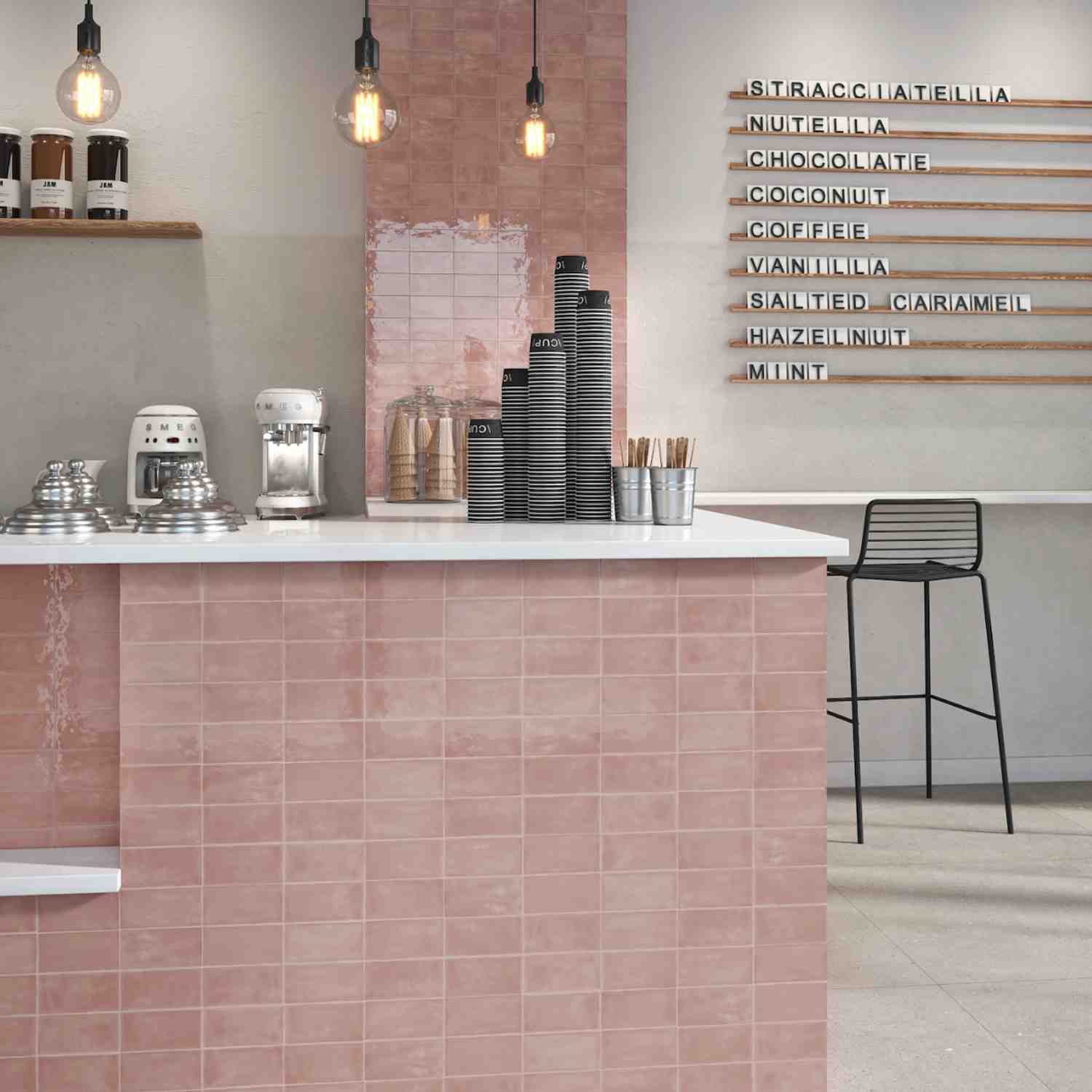 Terratinta Memorie Cipria pink glossy ceramic wall tiles in a café interior with white counter, letter board menu, Edison bulb pendant lights, and black wire bar stool